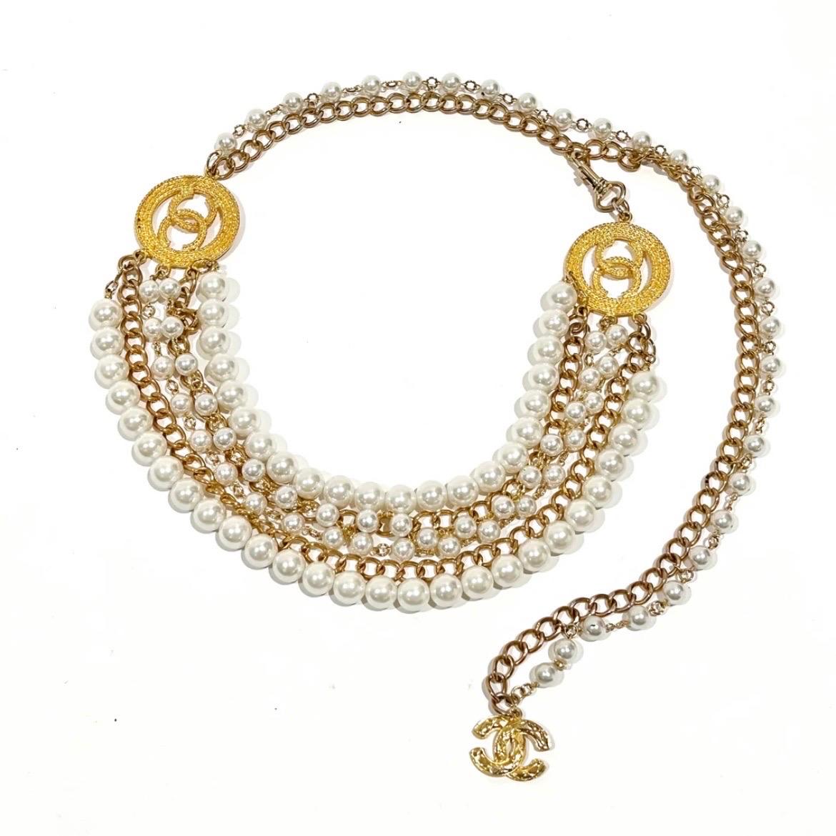 Multi-chain pearl belt by Chanel 
Circa 1980's
Made in France 
Gold-tone metal chain intertwined with strands of white pearl beads  
6 strands of chain/pearl drape detail 
Dual circular gold-tone logo pendants (on each side of drape detail)