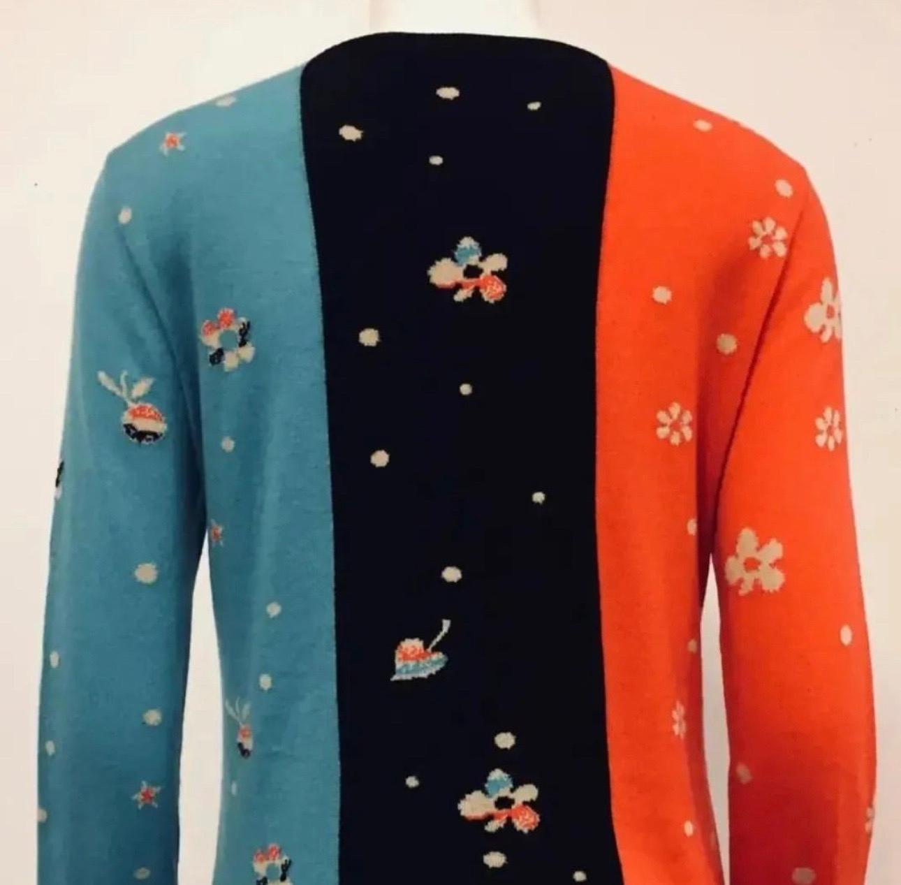 Chanel cashmere pullover sweater with whimsical print of man on a horse and Cupid with his arrow.
It's Chanel being playful! This round collar sweater with black knit trim and long sleeves features one in red and the other in turquoise. The front of