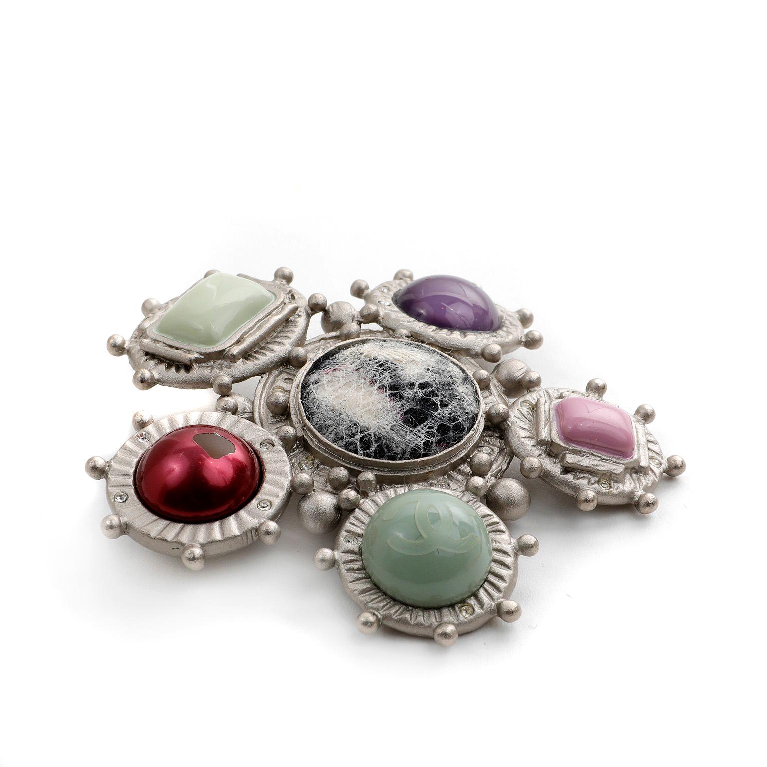 This authentic Chanel Multi Stone and Tweed Pin is in very good condition.  Five stones in different shapes and colors are situated around a central tweed pattern button.  Matte silver tone metal. 

PBF 11052

 