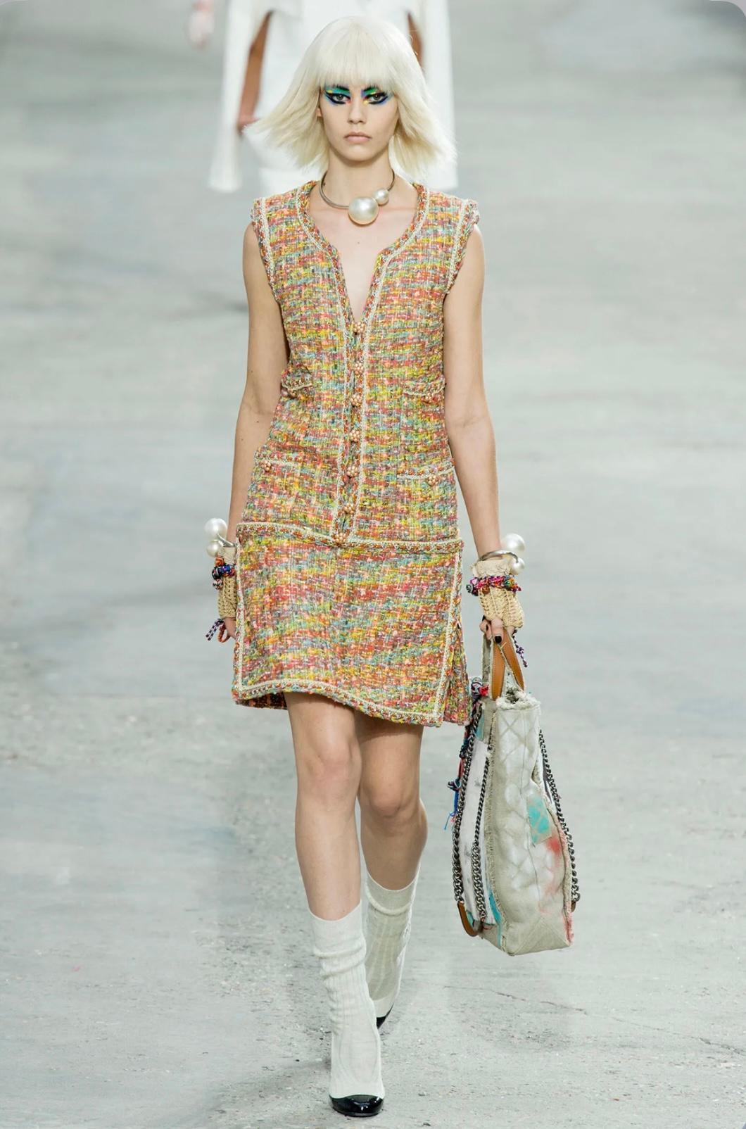 Como se vio en la pasarela Chanel de 2014, este impresionante vestido muestra la artesanía característica de la maison en un vibrante tweed bouclé multicolor, tejido con maestría con toques de hilo metálico dorado para un sutil brillo. La silueta
