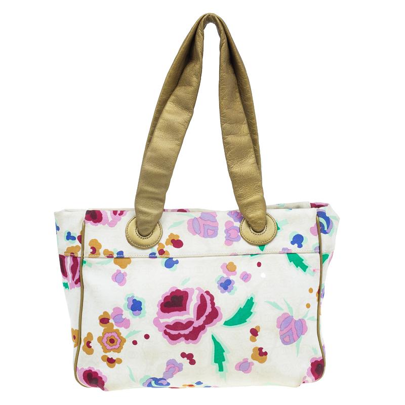 Bring the beach days with all your essentials when you carry this tote. This tote is made of floral printed canvas accented with golden leather and gold-tone hardware. It comes with a deep zip pocket in the front featuring a Coco Chanel charm and is