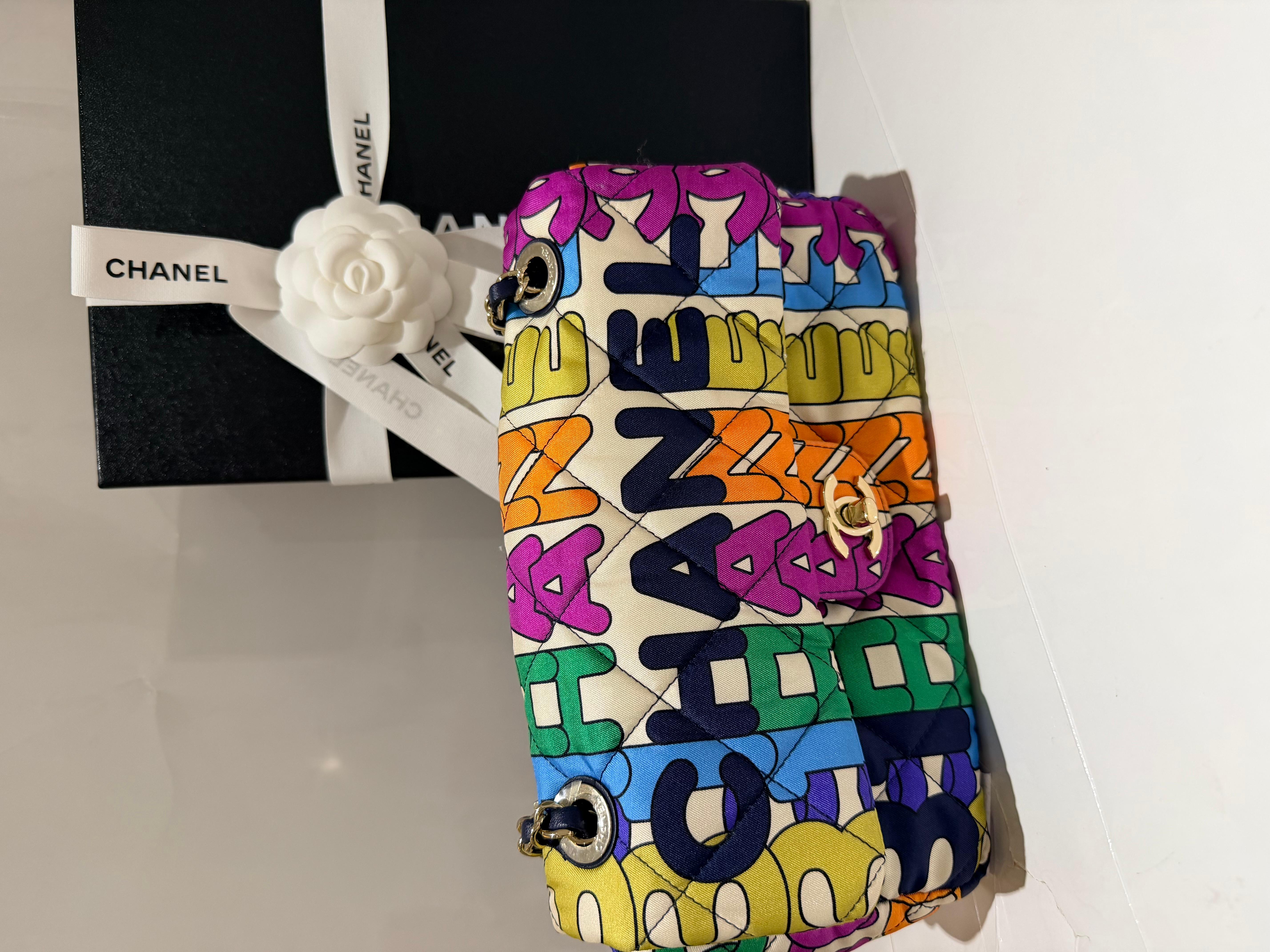 Chanel Printed Fabric Quilted Logo Single Flap Bag in Multicolor. This stylish bag is crafted of nylon quilted fabric. This bag features multicolor square pattern formation and navy blue shoulder straps. Iconic Chanel design

Collection: 2021 (RFID