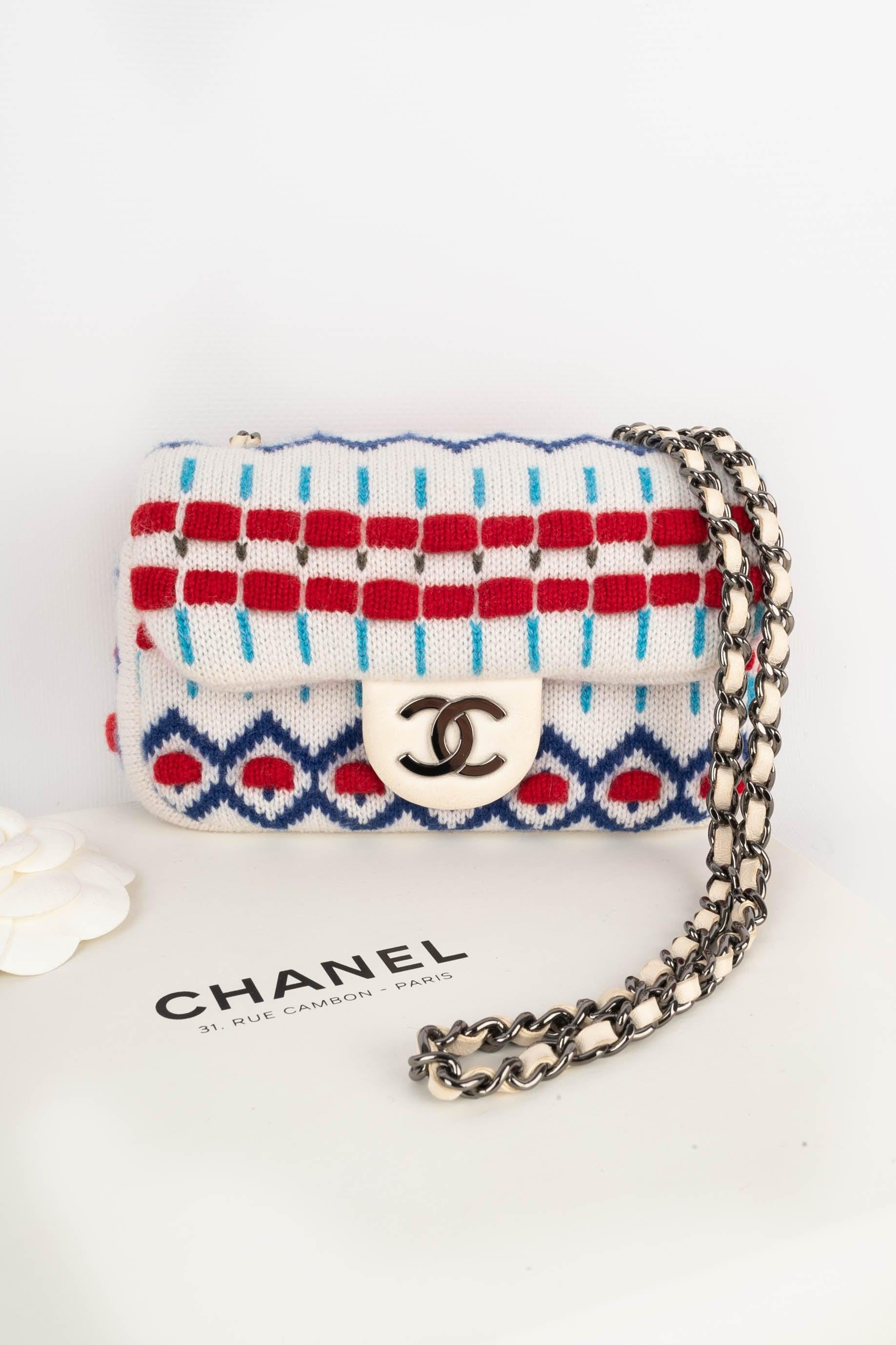 Chanel - (Made in France) Mini sac en laine multicolore à motifs scandinaves, fermeture à bouton pression magnétique sur un rabat, surmonté des initiales de la maison. Poignée en chaîne entrelacée. Pièce avec un numéro de série et un certificat de