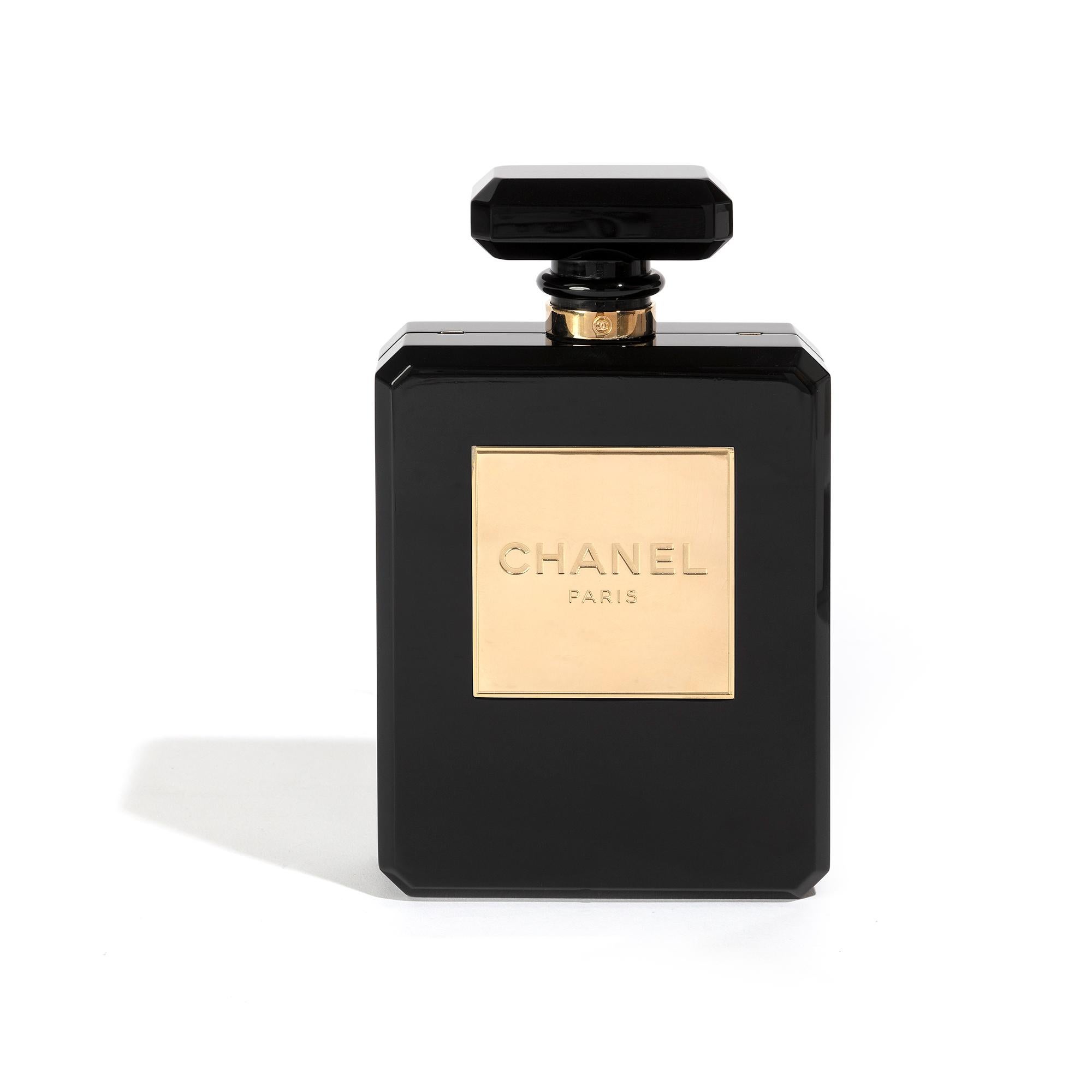 There are few symbols closer to the heart of the Chanel brand than a N5 perfume bottle. A rare collectors’ item, this Chanel N5 minaudière is crafted from black plexiglass, finished with pale gold-plated hardware, and a woven chain strap. A