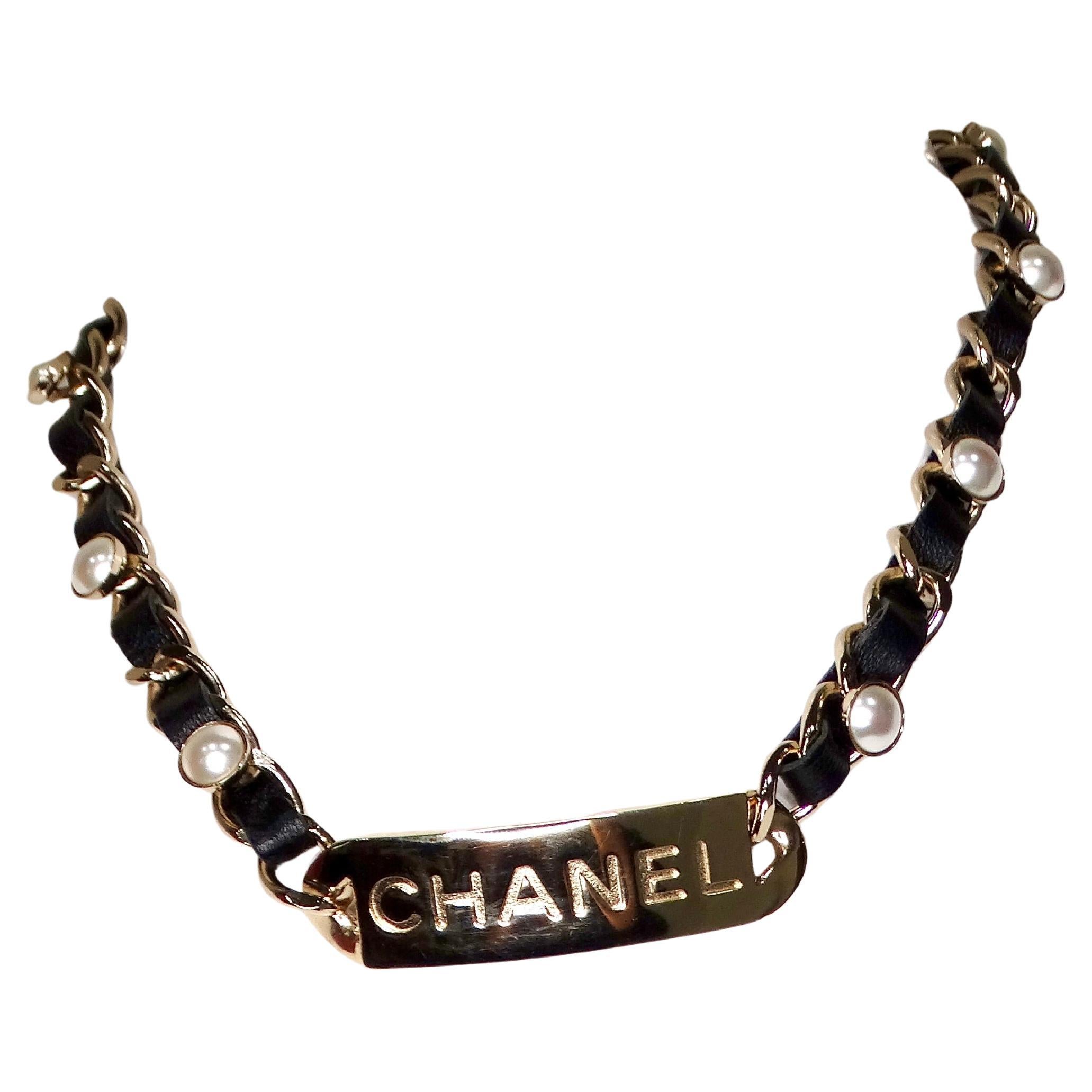La collana Chanel Name Plate Leather & Costume Pearl del 2019 è un pezzo lussuoso e sofisticato che fonde perfettamente l'eleganza classica con lo stile contemporaneo. L'elemento centrale di questa collana è la targhetta in oro con l'incisione