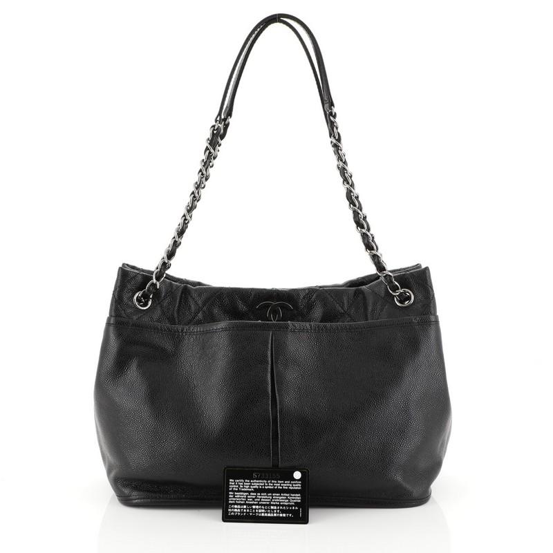 This Chanel Natural Beauty Tote Caviar, crafted from black caviar leather, features dual woven-in leather chain straps, quilted top trim, inverted pleats, and gunmetal-tone hardware. Its top magnetic snap closure opens to a black fabric interior