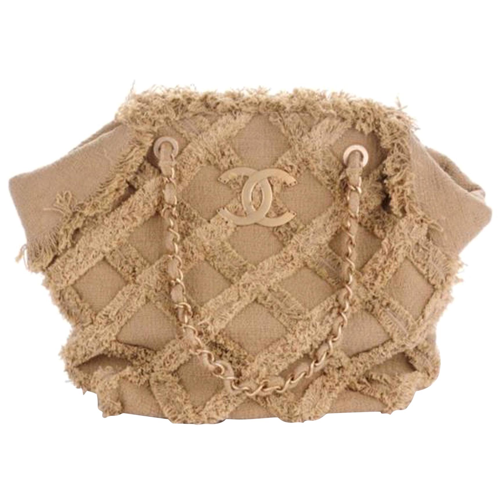This Chanel Nature Tote Quilted Tweed, crafted from beige quitled tweed, features diamond quilted top trims, dual woven-in leather chain straps, inverted pleats details, and matte gold-tone hardware. Its top magnetic snap closure opens to a beige
