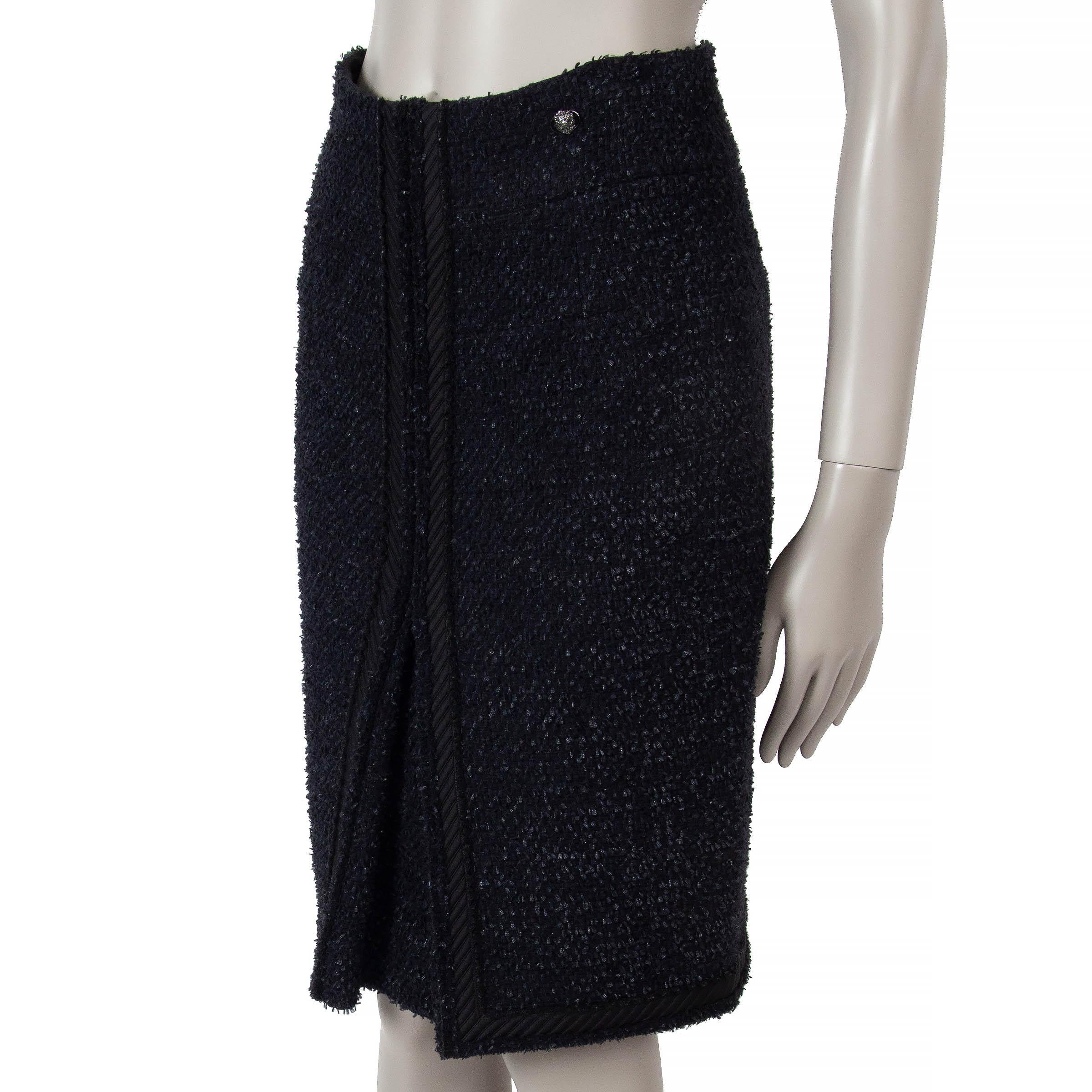 This 100% authentic Chanel tweed skirt in black and midnight blue wool (80%) and nylon (20%) showcases timeless elegance. Designed with a quilted trim and a signature logo button at the waist, it offers a refined silhouette. The skirt closes with a
