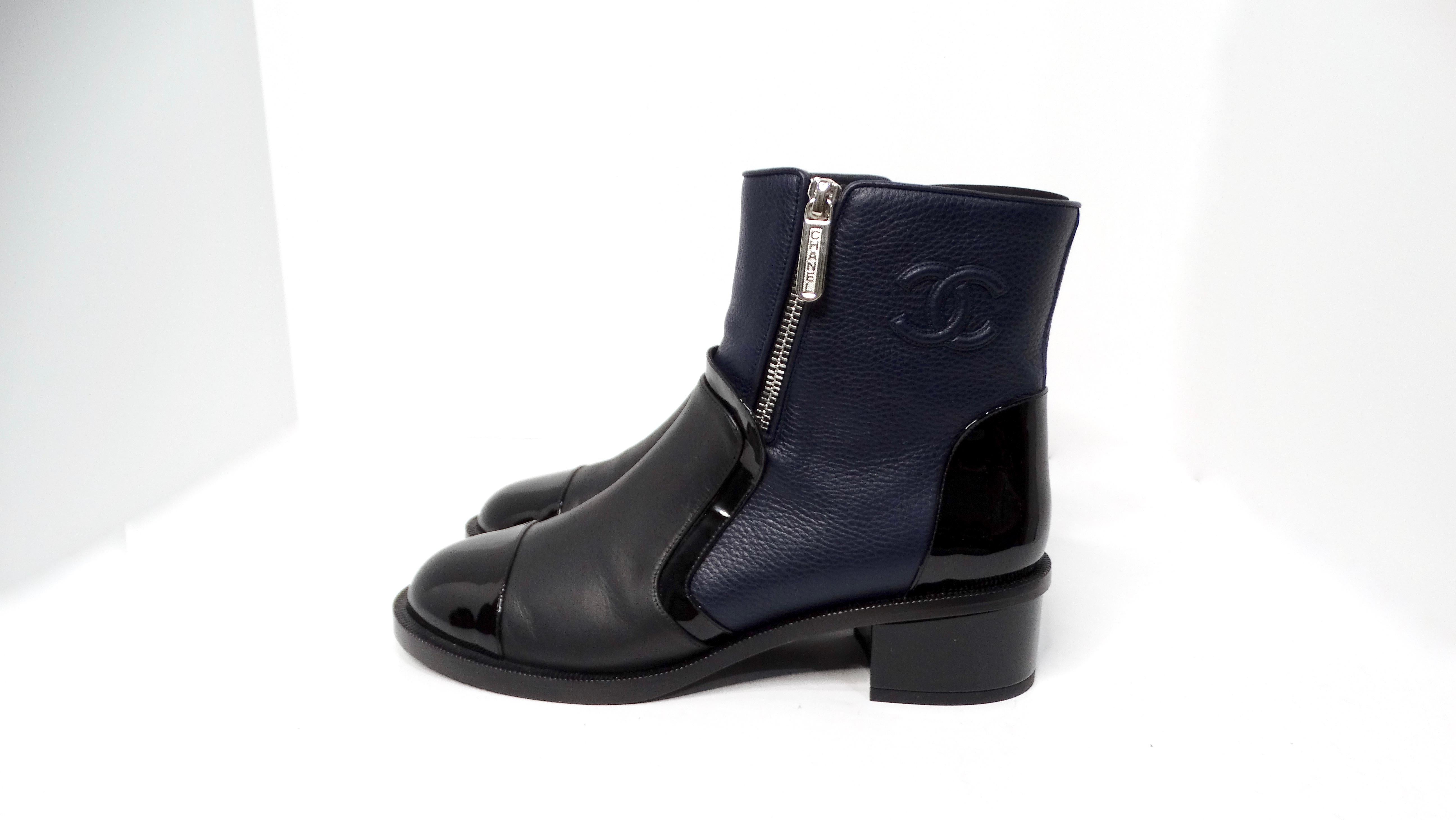 The Chanel Navy Blue & Black Leather Interlocking CC Logo Ankle Boots effortlessly combine classic elegance with modern flair. These beautifully crafted ankle boots feature a chic two-tone design, showcasing a rich navy blue leather that contrasts