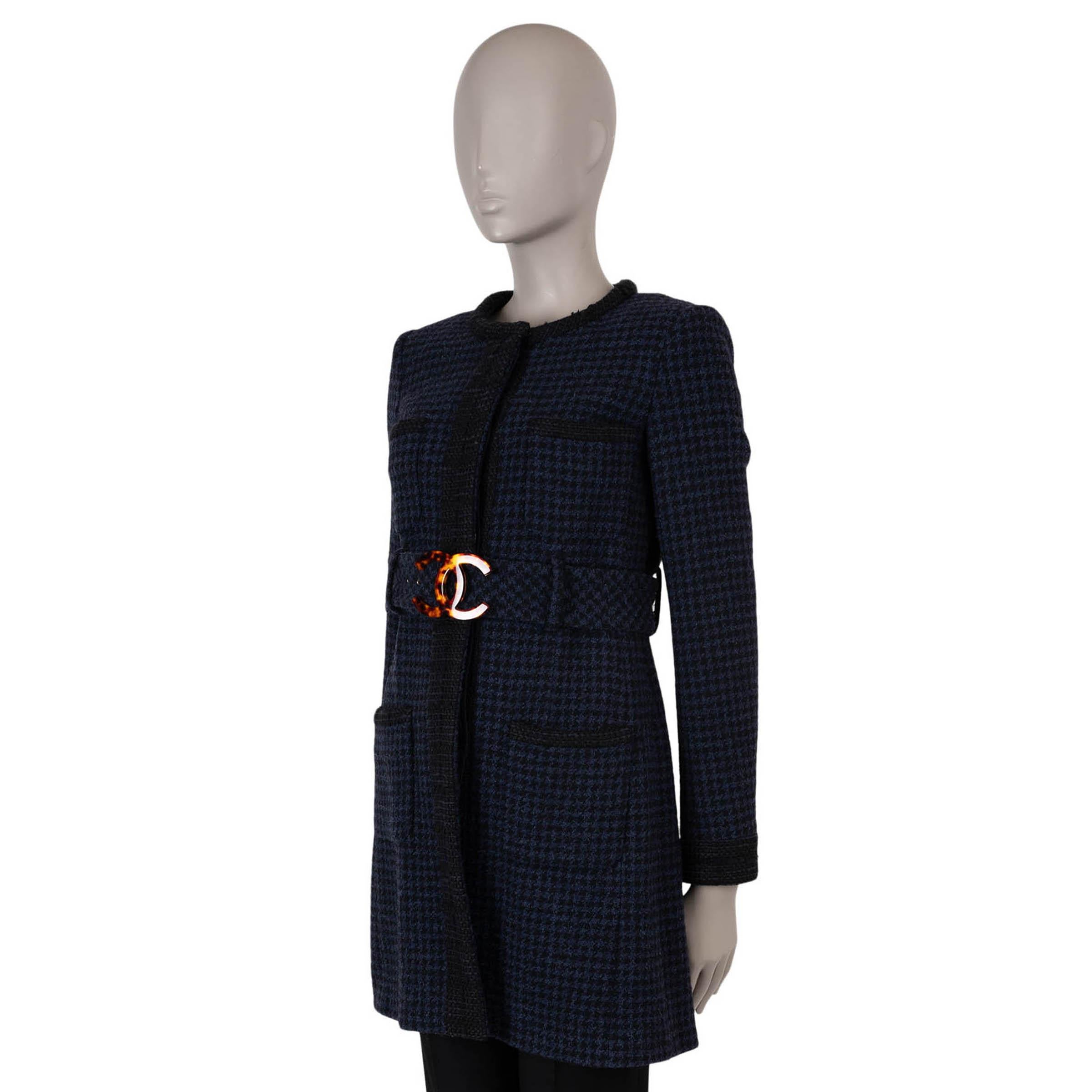 This 100% authentic Chanel coat in navy blue and black houndstooth tweed wool (80%), nylon (14%), and rayon (6%) showcases timeless sophistication. Designed with a collarless, straight silhouette and knee length, it features contrasting black woven