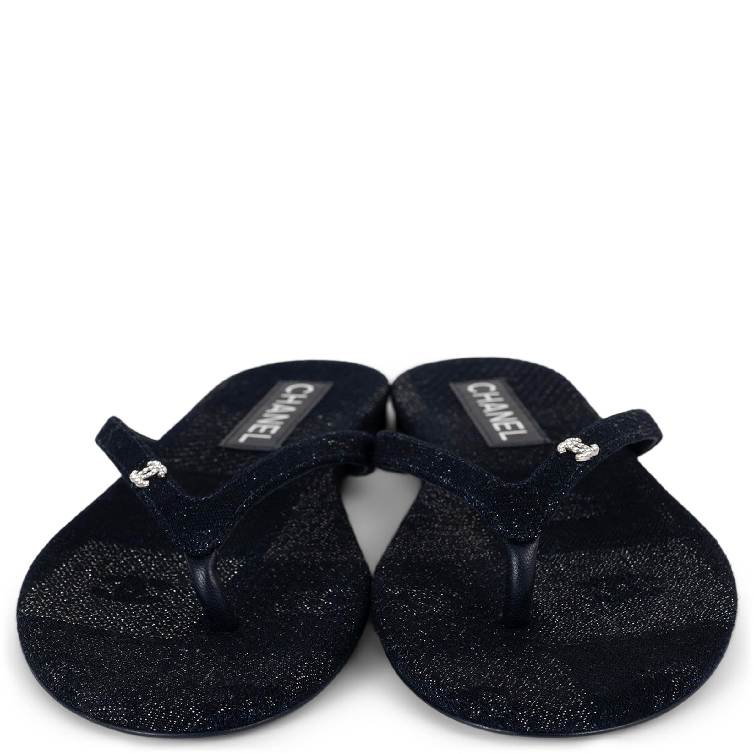 This 100% authentic Chanel thong sandals are crafted in navy blue and silver glitter canvas, a cotton-silk blend that adds a refined shimmer to a casual silhouette. Designed in the classic flip-flop style with rounded toes, they are finished with a