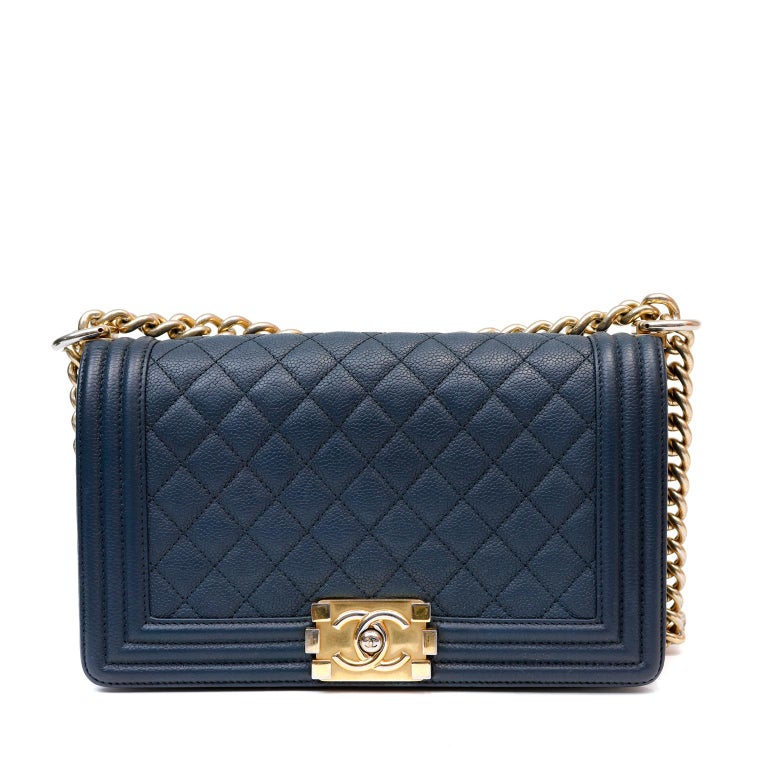 This authentic Chanel Navy Blue Caviar Medium Boy Bag is in excellent condition. The updated design is structured and edgy with a versatility that makes it extremely popular.  Navy blue caviar leather is textured and durable. Further quilted in