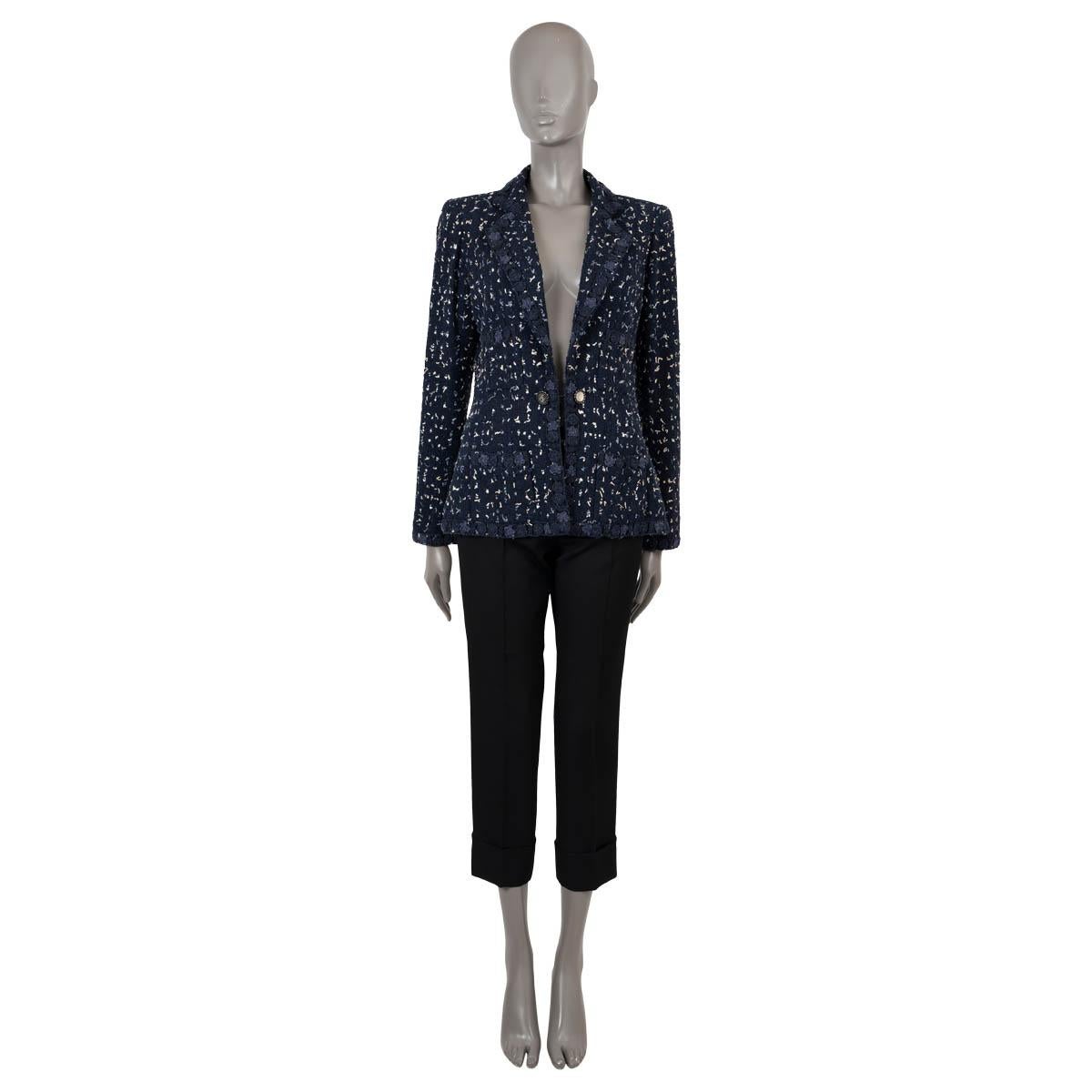 100% authentic Chanel tweed jacket in navy blue cotton (53%), polyamide (33%) and viscose (14%) with white and light blue mini fringe. Features a tailored silhouette, peak lapel, four patch pockets and Camellia application trim. Closes with a silver