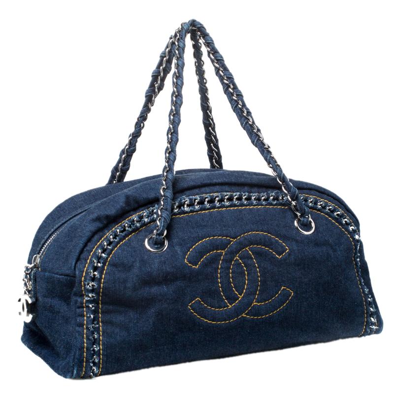 Make a statement when you swing this bag from Chanel. Fabulously crafted from navy blue denim and designed with chain trims and the CC logo on the front, this bowler bag is a beauty! A zip closure secures a spacious fabric interior and the bag is