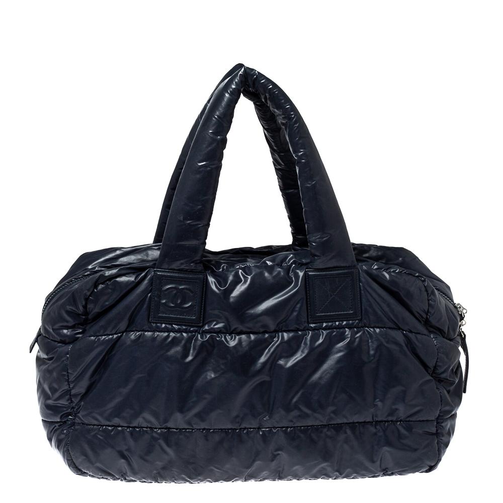 This luxurious Coco Cocoon bowler bag by Chanel is a note-worthy design. Crafted with quilted nylon, it features dual top handles and silver-tone hardware. This bag has a top zip-up closure that reveals a nylon-lined interior sized to assist you