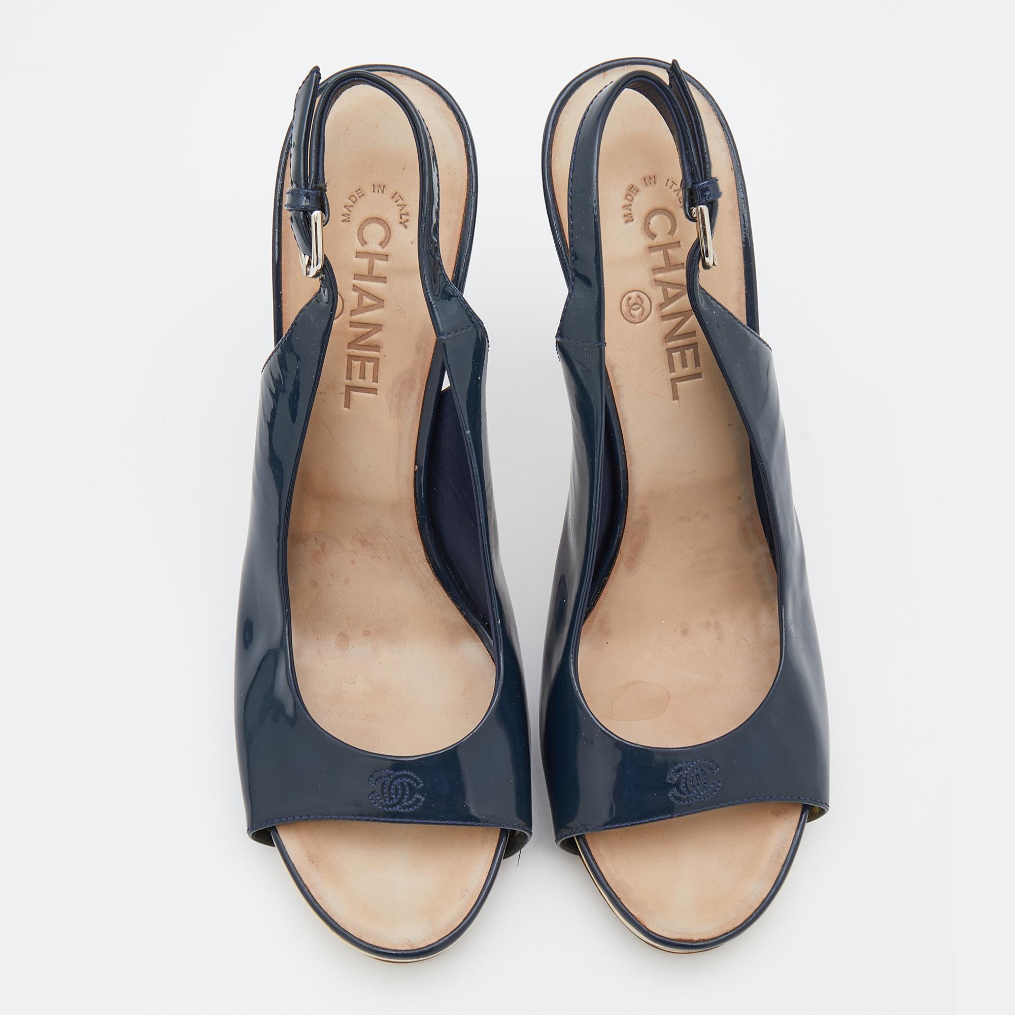 Alliant confort et élégance, ces sandales Chanel à boucle et bride sont indispensables à votre garde-robe. Réalisé en cuir verni bleu marine, ce modèle à bout ouvert est doté d'une plateforme. Les escarpins sont dotés d'une semelle intérieure qui