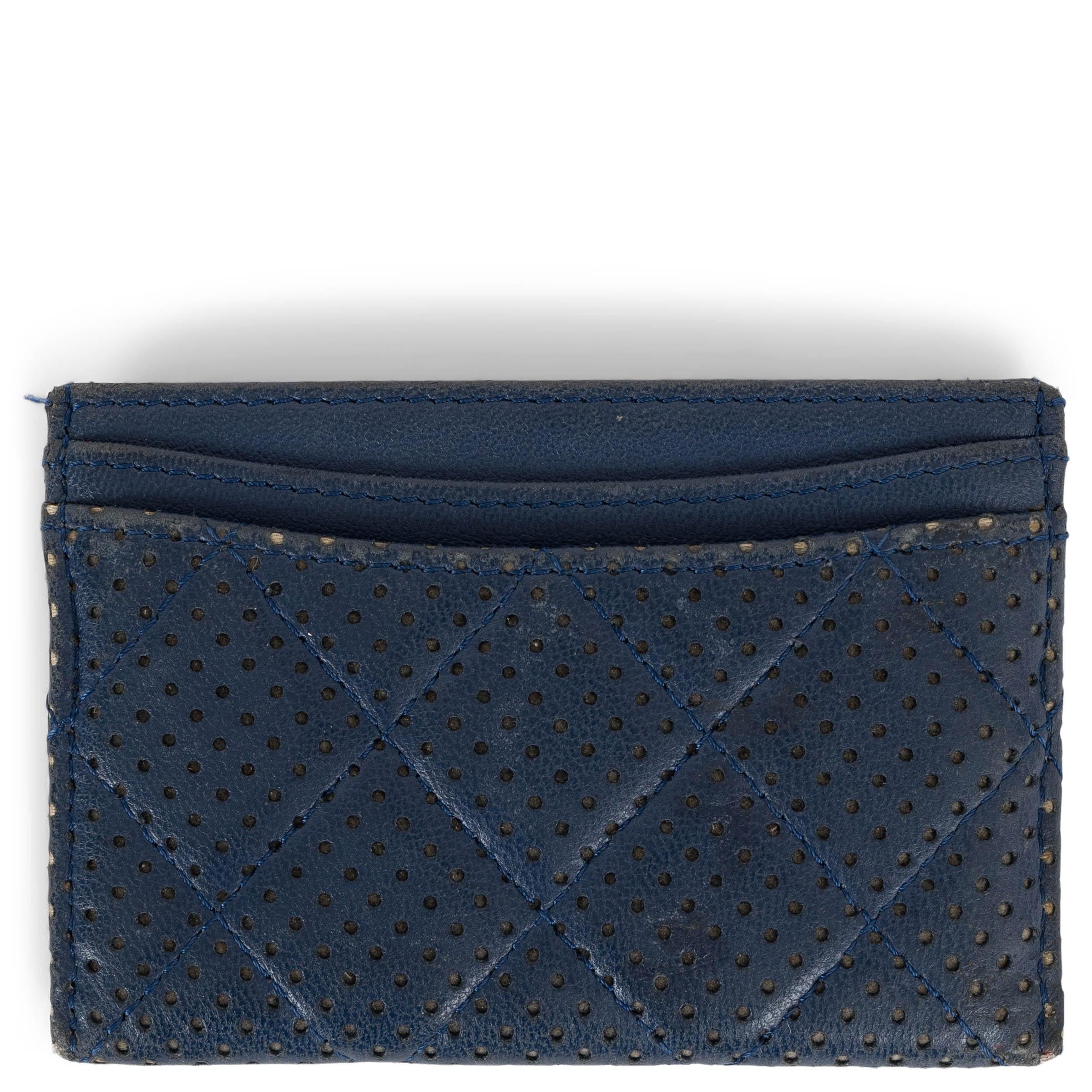 Questo portafoglio per carte di credito Chanel, autentico al 100%, è realizzato in pelle traforata color navy e offre una visione elegante e moderna del lusso quotidiano. Il design compatto è impreziosito dal logo CC argentato sulla parte anteriore,