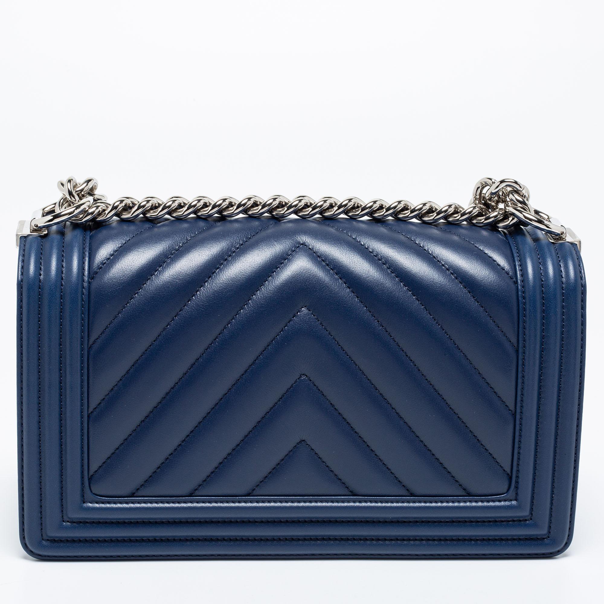 This medium Boy Flap bag from the House of Chanel is truly a pièce de résistance in the world of luxury fashion. It is crafted using navy-blue quilted leather, with a silver-toned CC accent placed on the front. This bag is held by a sturdy chain