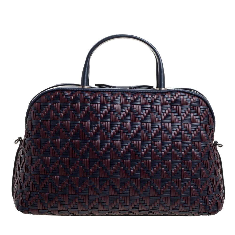 Spacious and captivating, this Bowler bag is from Chanel. It has been crafted from woven leather and features a beautiful combination of navy blue and red hues. It is equipped with two top handles and a well-sized fabric compartment to keep your