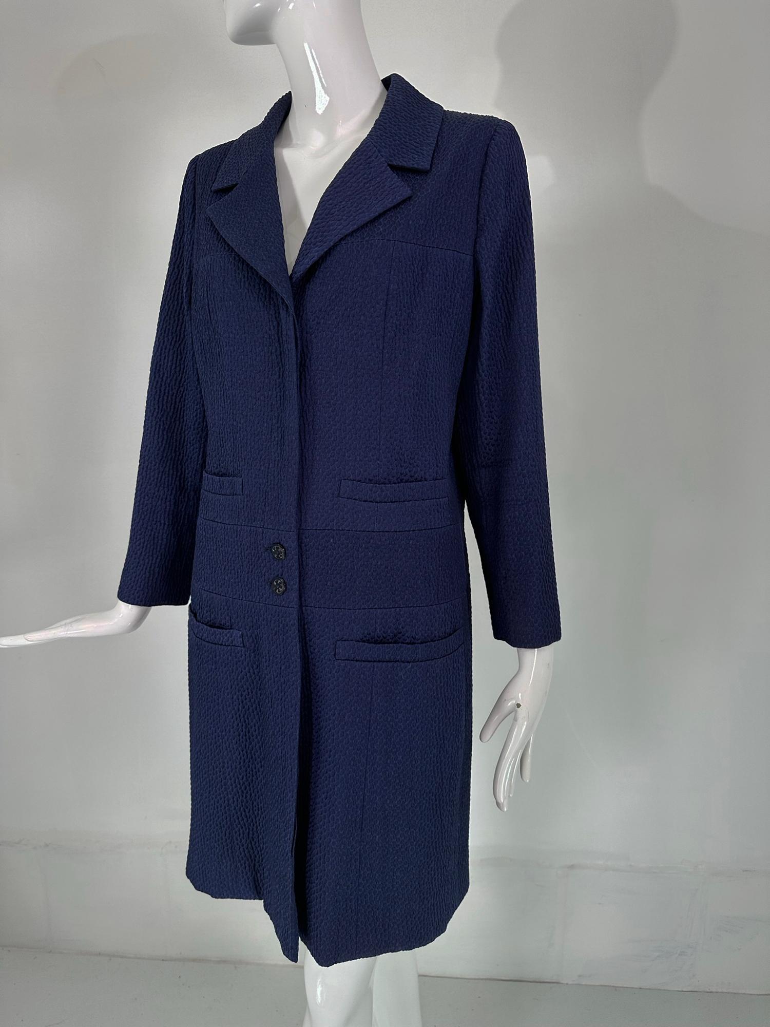 Chanel navy blue single breasted 4 pocket cloque cotton coat fits a size 4. Classic single breasted coat with a notched lapel collar, placket front closure, two blue Chanel buttons at the waist, the Chanel buttons at the top & below the waist are