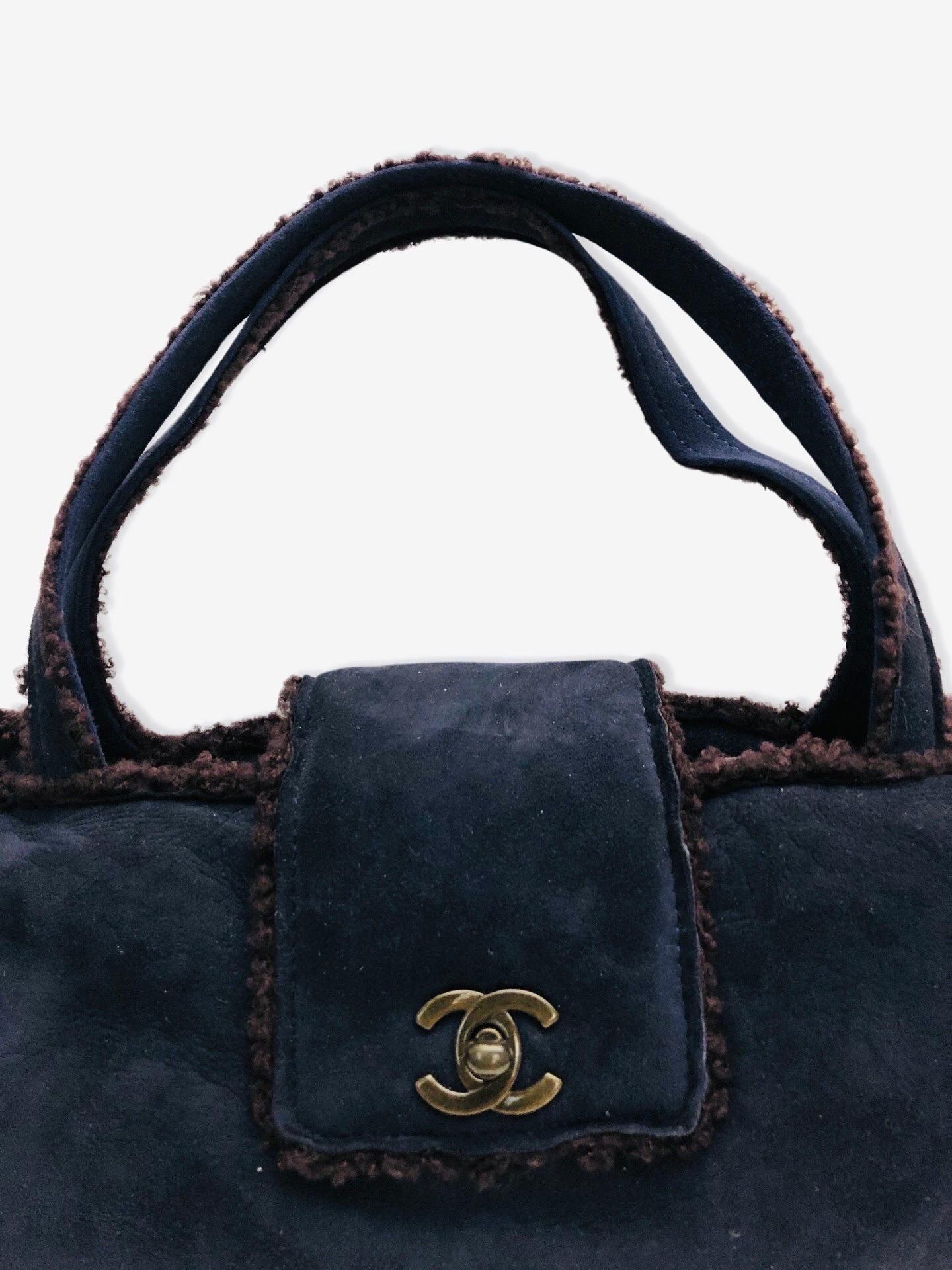 - Chanel navy blue suede shoulder shoulder handbag from 1998 collection. 

- Featuring brown shearling mouton trim overall. 

- CC turnlock flap closure. 

- Interior zip pocket. 

- Length: 32cm. Height: 16cm. Width: 7.5cm. Handle Drop: 18cm