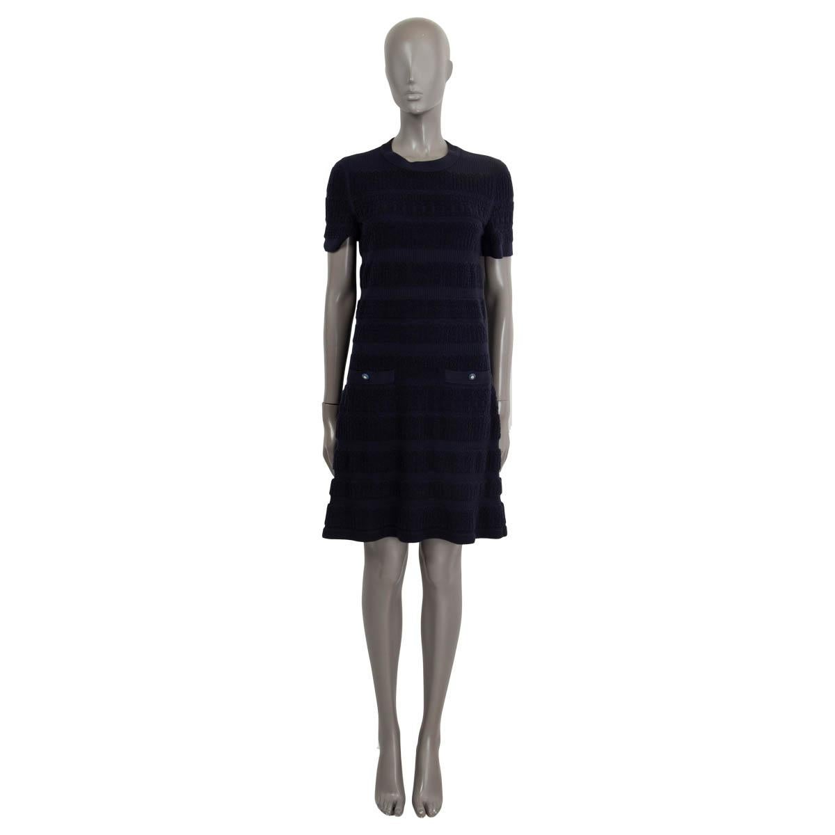 100% authentique Chanel robe en maille côtelée texturée en laine bleu marine (avec 4% de polyamide). Il comporte des manches courtes, deux poches fendues boutonnées cousues sur le devant et un col ras du cou. S'ouvre par des boutons CC dans le dos.