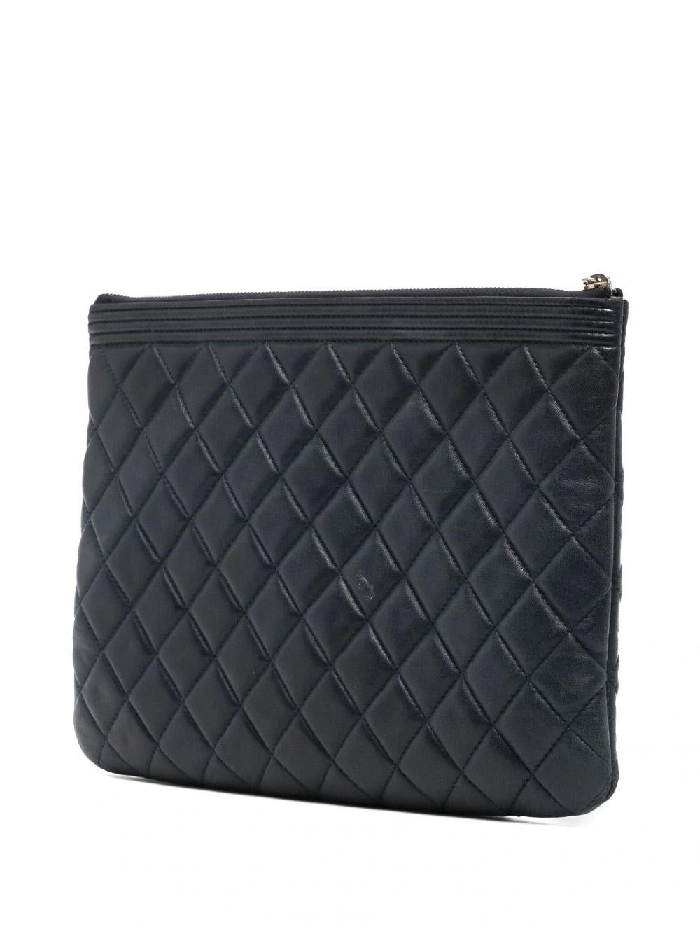 This Chanel Boy clutch bag is composed of dark blue leather in a diamond quilted pattern with a signature Boy push-lock motif and gold-tone hardware. It features a top zip fastening which leads to a main compartment. Luxurious, timeless, and