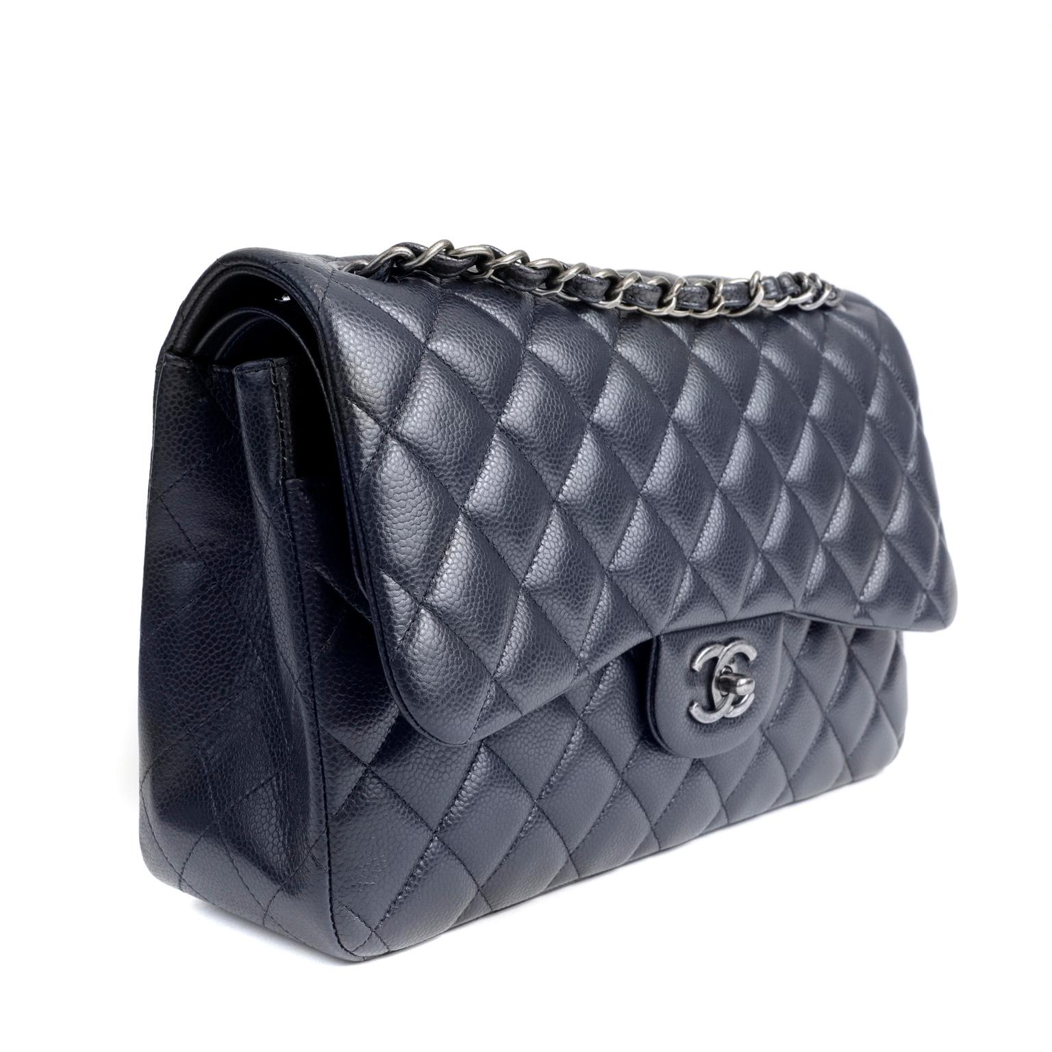 This authentic Chanel Navy Caviar Jumbo Classic Flap Bag is in pristine condition, appearing never carried.  A key piece in any sophisticated wardrobe, the Jumbo Classic is one of the most sought-after Chanel styles produced.
Durable and textured