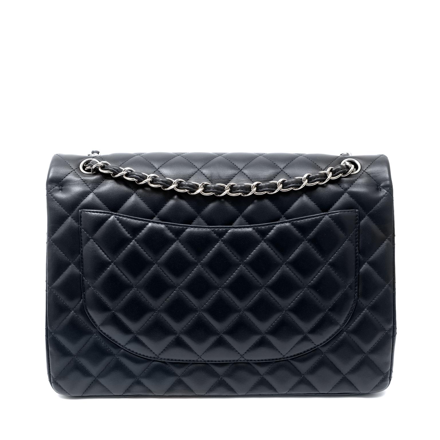 This authentic Chanel Navy Lambskin Maxi Flap Bag is in pristine condition.  In a very deep shade of navy, it appears nearly black.  This adds to the versatile nature of the classic Maxi.
Deep navy blue lambskin is quilted in signature Chanel