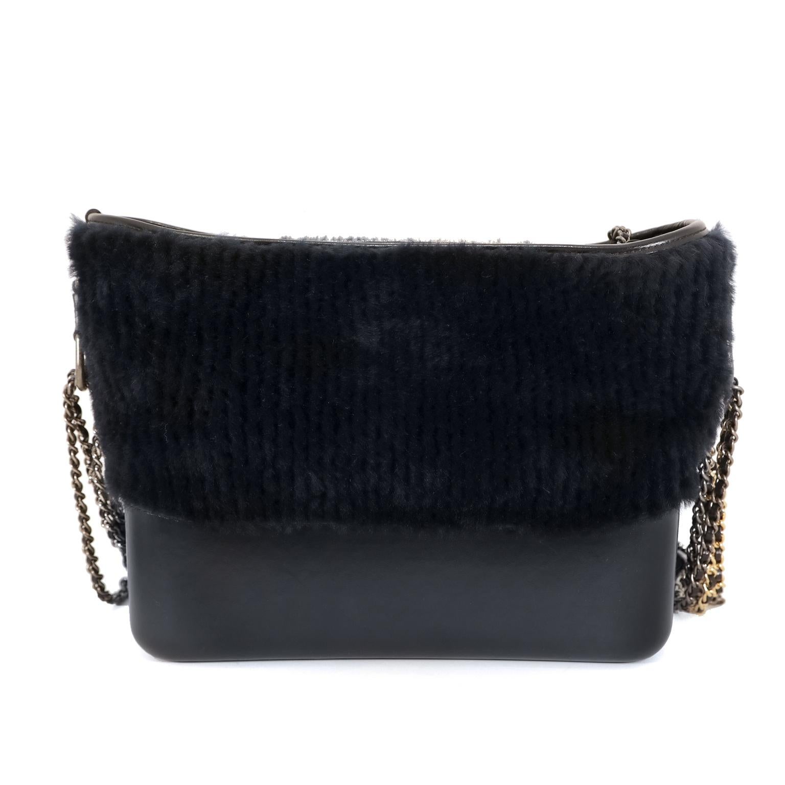This authentic Chanel Navy Shearling and Leather Gabrielle Bag is in very good condition.  
Midnight blue lambskin and shearling fur combine beautifully with gold and silver hardware accents.  Zippered top accesses the clean fabric interior. 