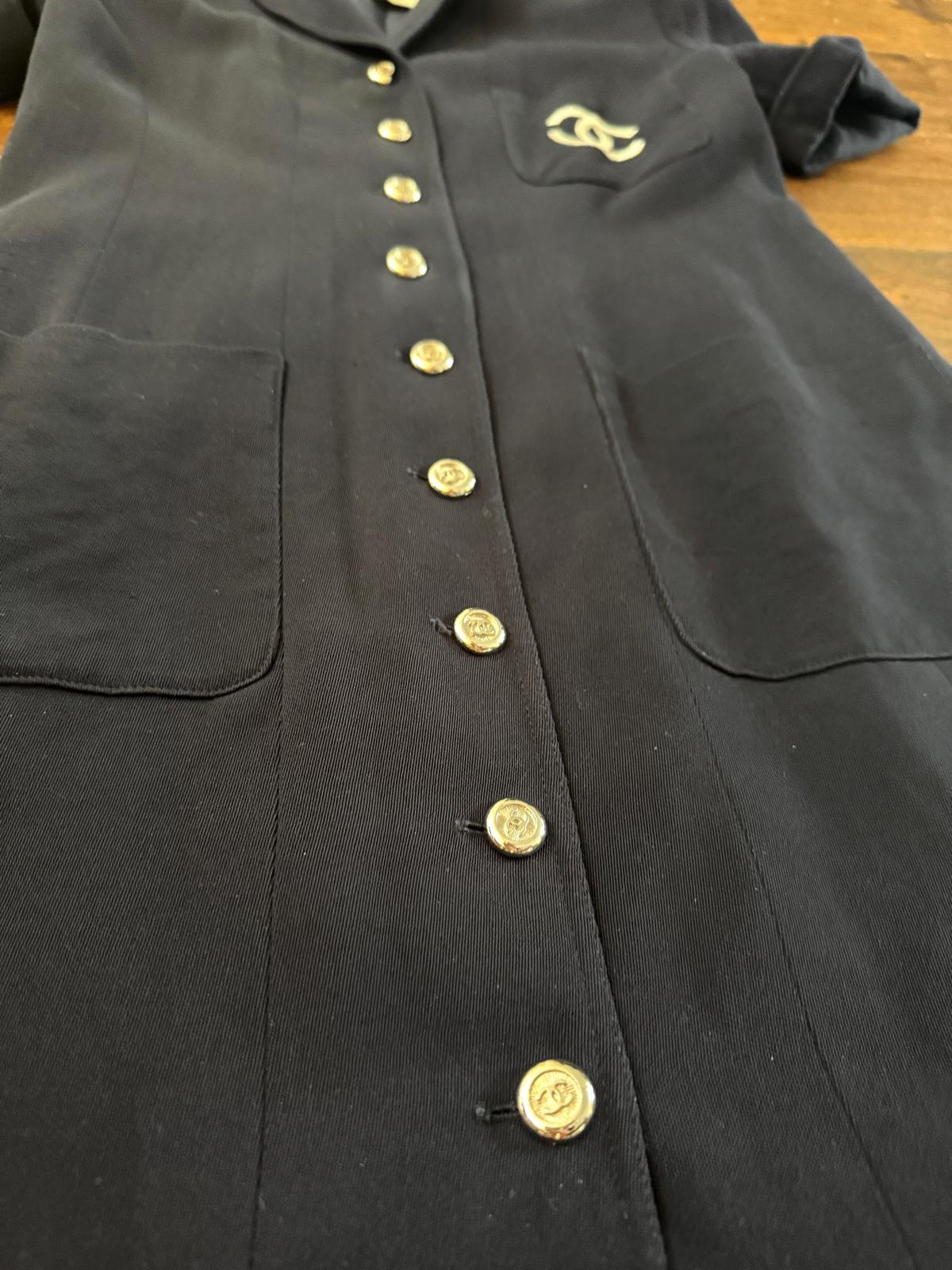 Chanel navyfarbenes, kurzärmeliges Button-up-Kleid in Größe 44. 

Kann als Kleid getragen oder offen als leichter Mantel gestylt werden. Mit CC Logo-Stickerei auf der Vordertasche und CC Logo-Knöpfen auf der Vorderseite.

Insgesamt in gutem