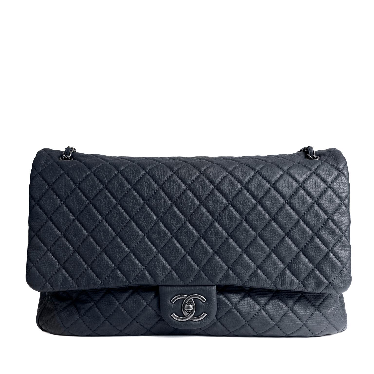 This authentic Chanel Navy Classic Travel XXL Flap Bag is in pristine condition.  Most certainly the chicest way to travel, this extra-large Classic Flap will get you there in style.
Deep navy-blue textured calfskin is quilted in signature Chanel