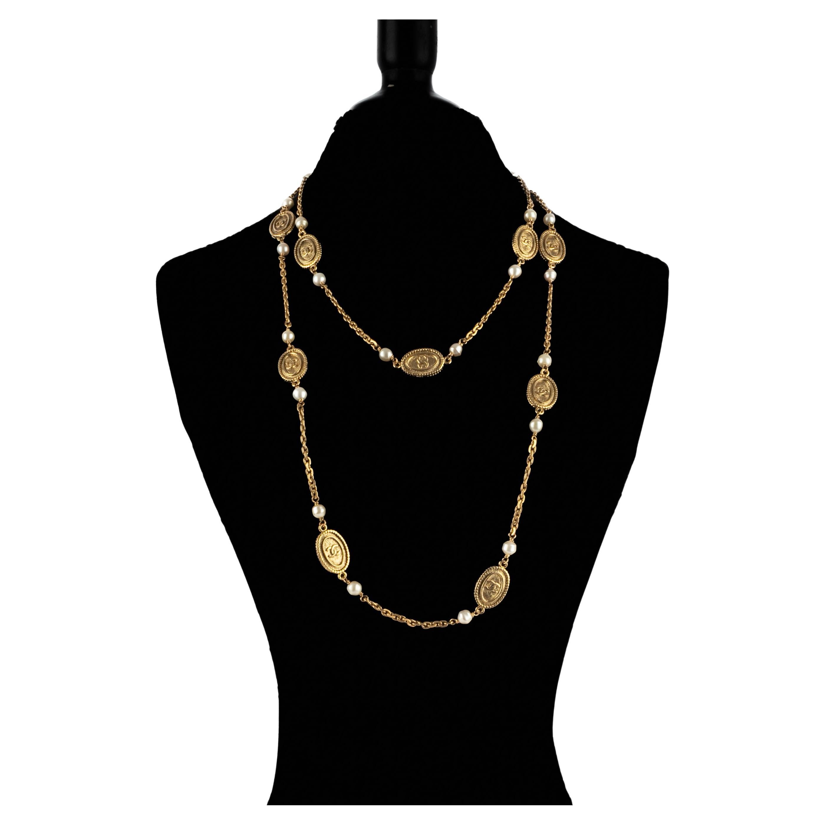 CHANEL - (Made in France) Long golden metal necklace with cc medallions and tiny costume pearls. Jewelry from the early 1980s.

Condition:
Very good condition

Dimensions:
Length: 150 cm

SKU:CB240
