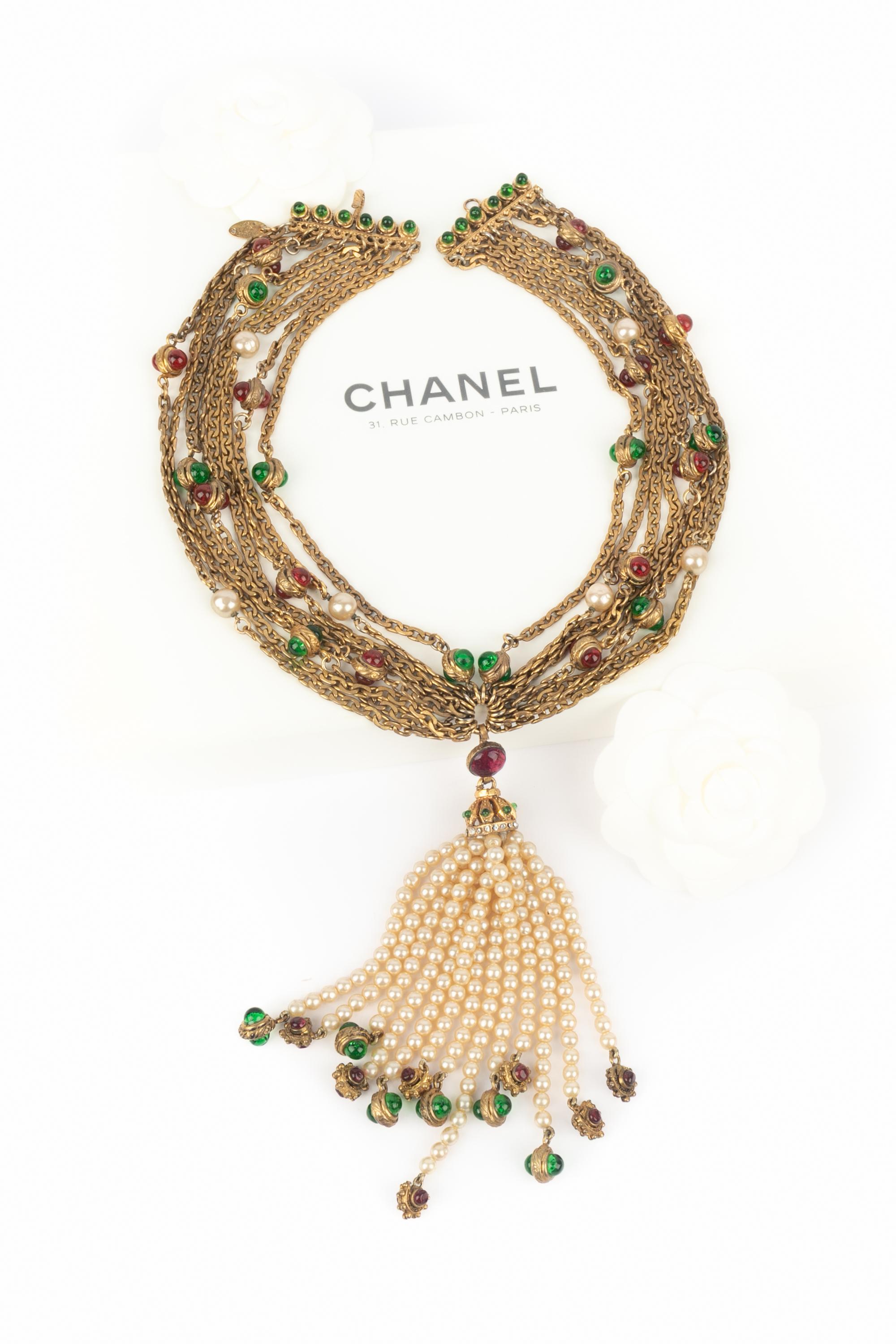 CHANEL - (Fabriqué en France) Collier à plusieurs rangs de chaînes en métal doré, orné de pâte de verre, de perles fantaisie et d'un pompon assorti. A 1984 Collectional.

Condit :
Très bon état.

Dimensions :
Longueur : 45 cm

SKU:CB5


