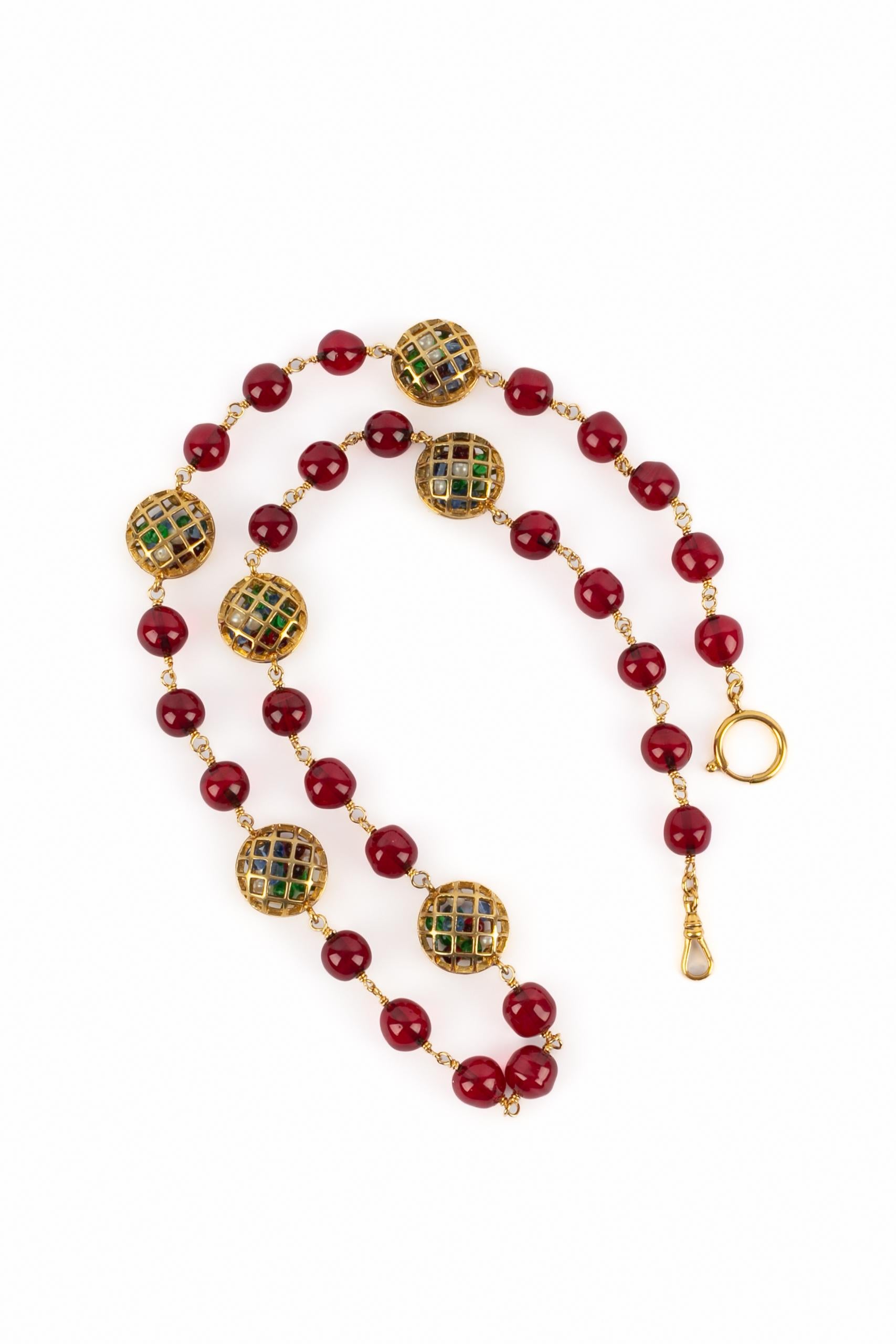 CHANEL - (Fabriqué en France) Long collier de perles de verre rouge avec des éléments en métal doré représentant de minuscules cages contenant de minuscules perles. Bijoux des années 1990.

Condit :
Très bon état.

Dimensions :
Longueur : 76