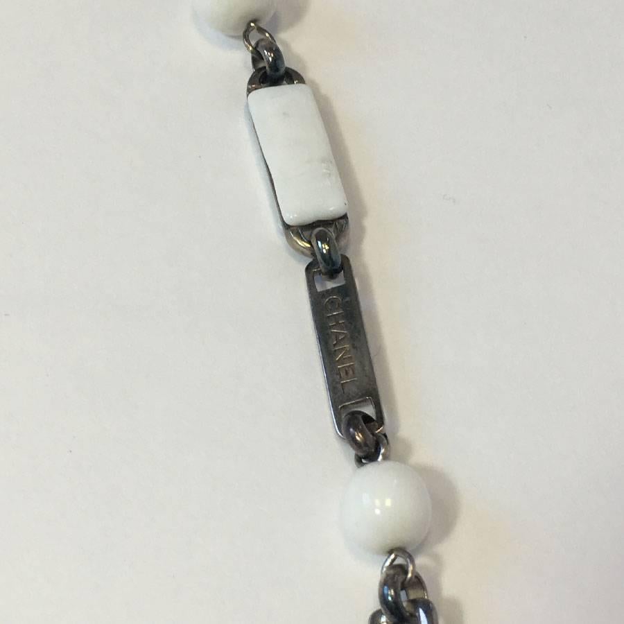 Very beautiful Chanel necklace-belt in white and transparent molten glass. Silver metal chain. Camellia hook clasp in molten glass.

In excellent condition.

Dimensions: total length: 89 cm, worn on the last ring: 87 cm. It can adapt to all sizes up