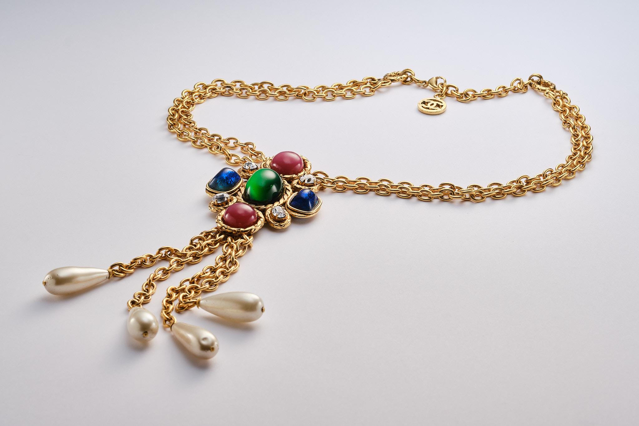 
2 row chain with a large cross-shaped pendant, decorated with pink , blue and green glass cabochons and rhinestones. On it hang 4 chains 8 cm long with beautiful pearl drops.
The chain is designed by Victoire de Castellane, the metalwork by