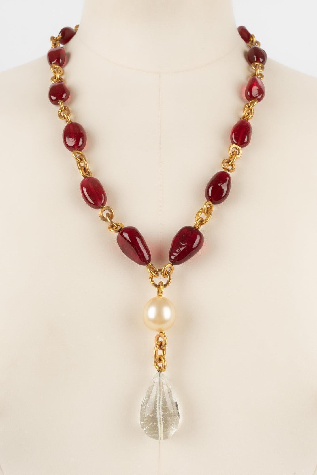Chanel - Golden metal necklace with red glass pearls holding a costume pearl and a glass paste drop. Jewelry from the Coco era, seen on Coco Chanel. Not signed.

Additional information:
Condition: Very good condition
Dimensions: Length: from 55 cm