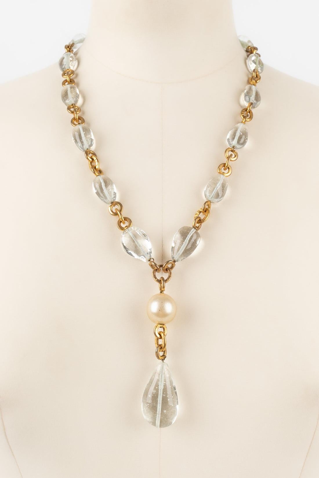 Chanel - Golden metal necklace with transparent glass pearls holding a costume pearl and a glass paste drop. Jewelry from the Coco era, seen on Coco Chanel. Not signed. To be noted, the pearly material is damaged.

Additional information:
Condition: