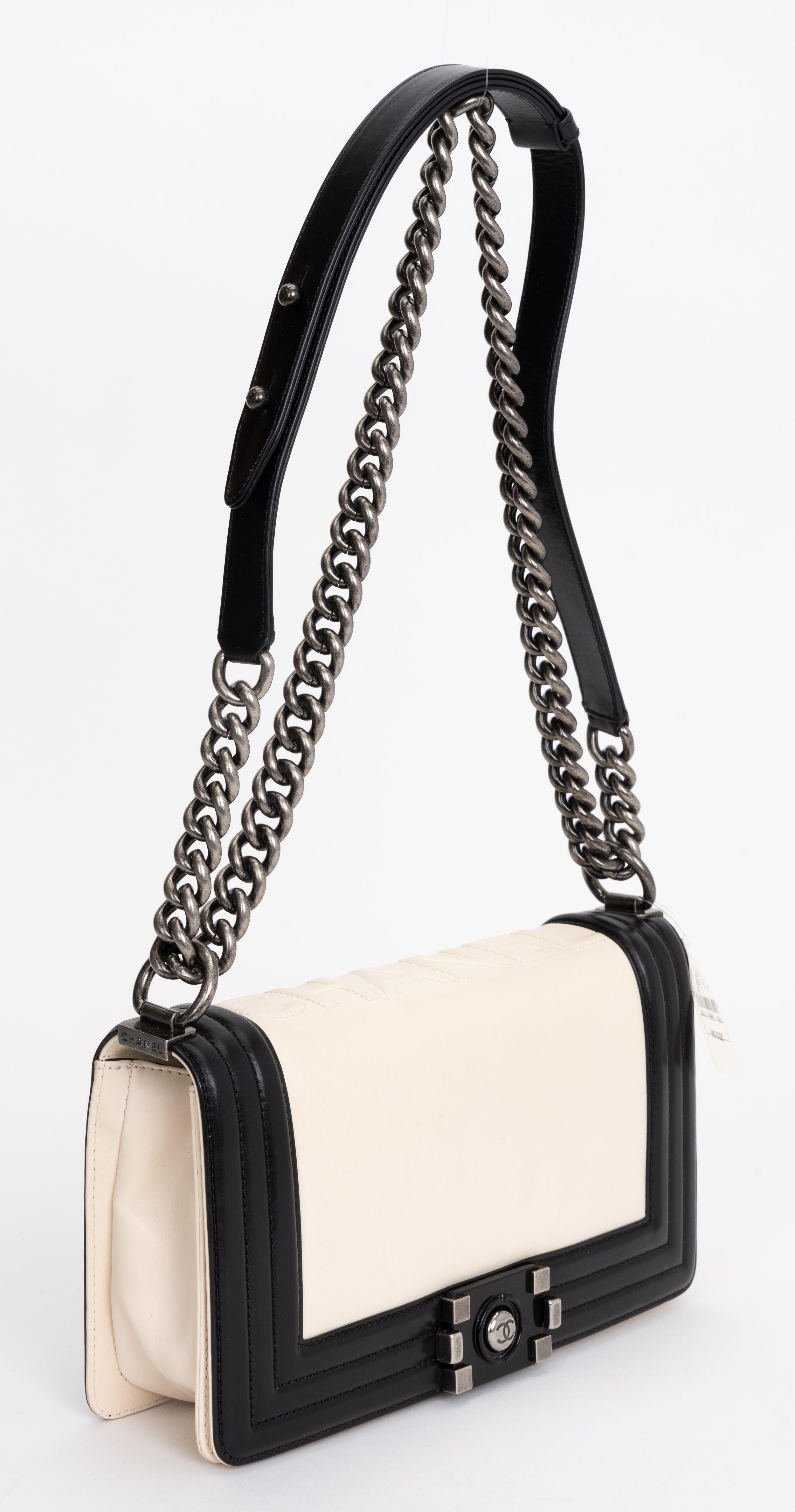 The Chanel Glazed Calfskin Boy Flap bag features smooth leather in Black and White. The aged silver chain shoulder strap makes the bag versatile. Includes patch pocket in the interior. The shoulder drop 19