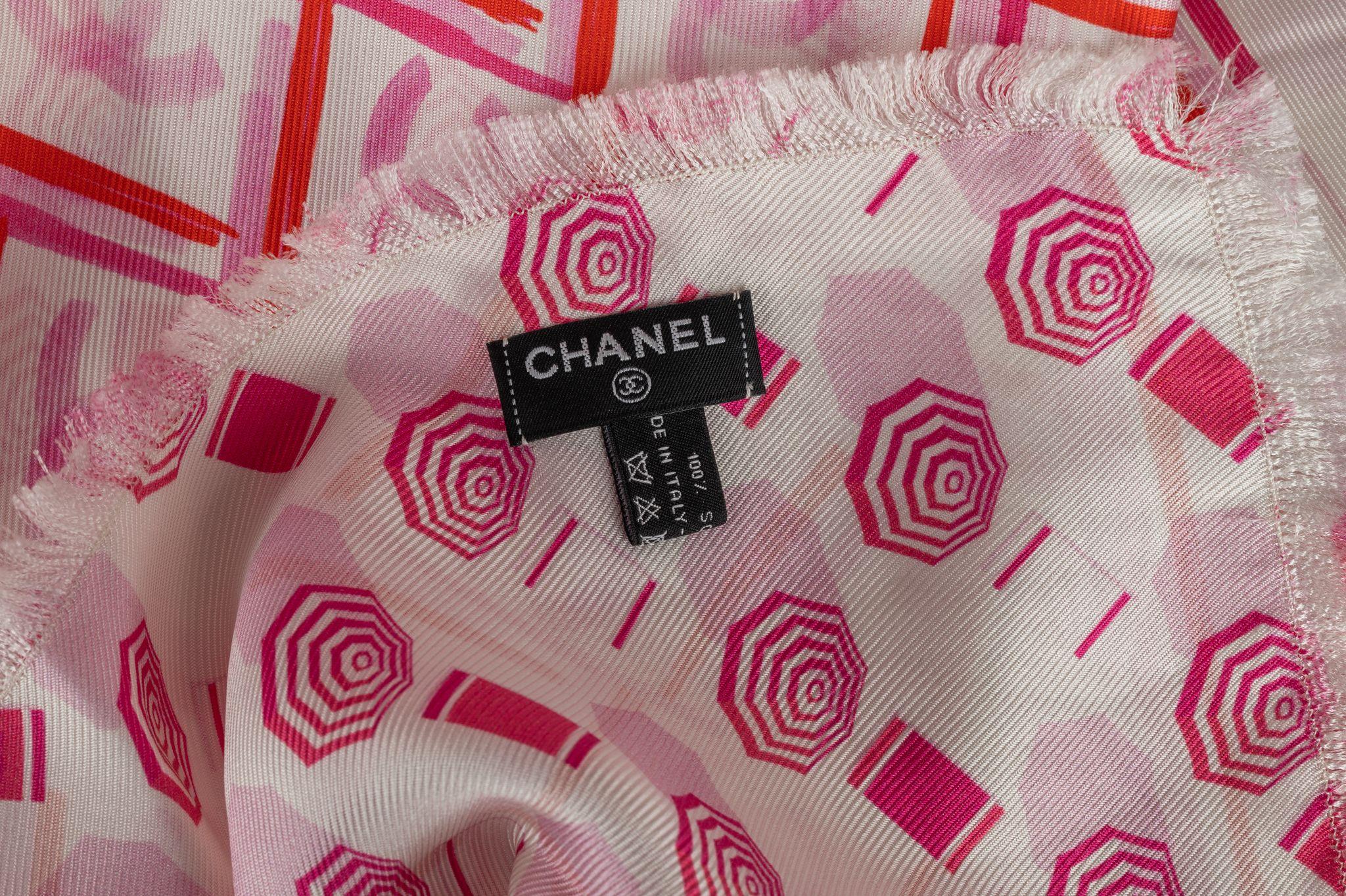 Chanel Silk Shawl in pink and white. The pattern features a geometric design with CC logos and beach umbrellas. The item is in excellent condition.