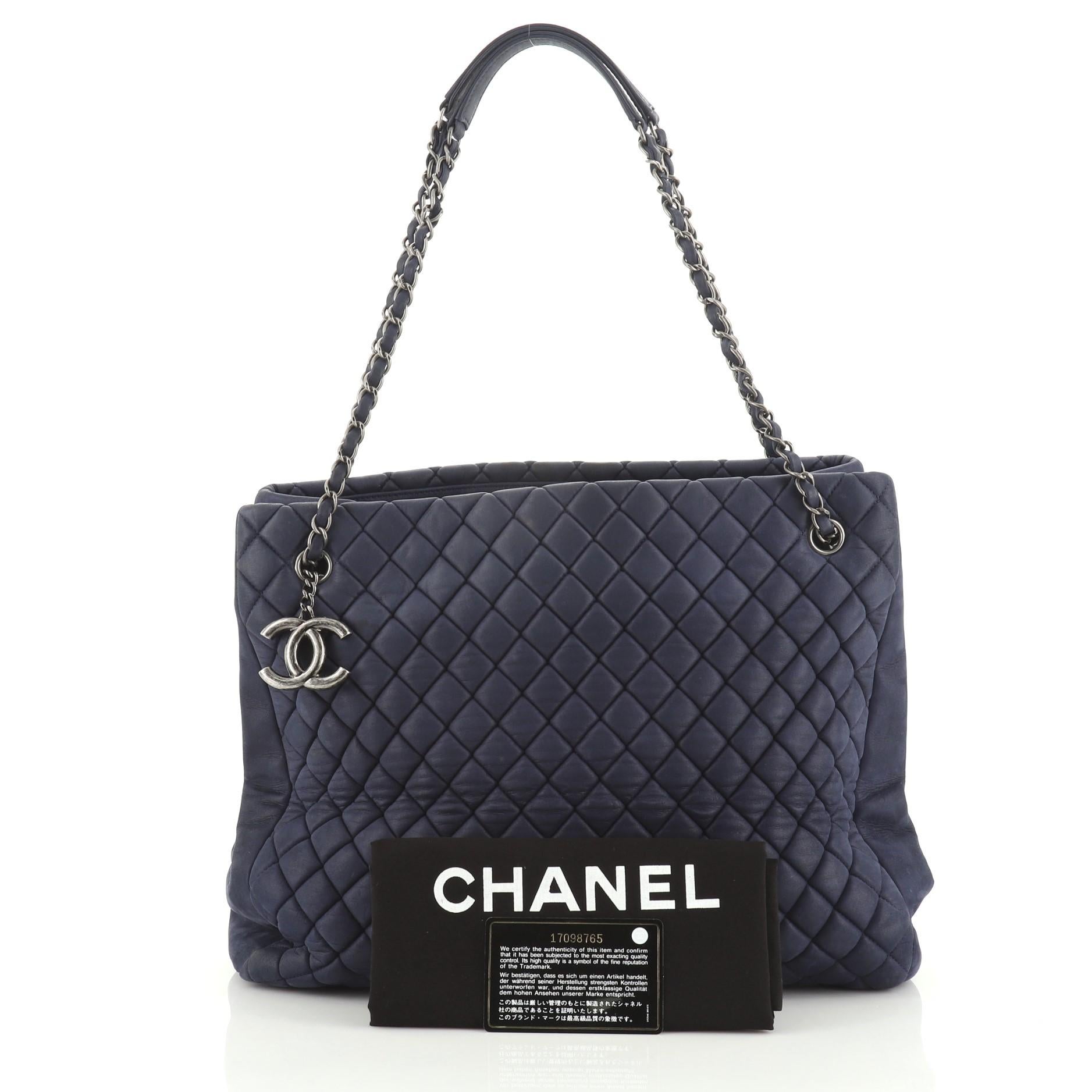 This Chanel New Bubble Tote Quilted Calfskin Large, crafted from blue quilted calfskin leather, features woven-in leather chain straps with leather pads and aged silver-tone hardware. It opens to a blue fabric interior. Hologram sticker reads: