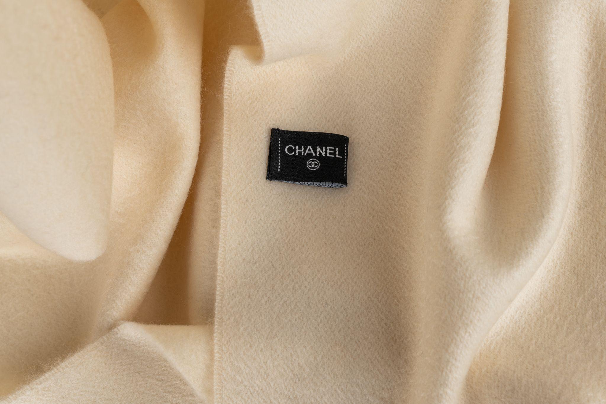 Chanel Cashmere Shawl in beige with fringes. The scarf also features a print of the Chanel rose. Item is in new condition.