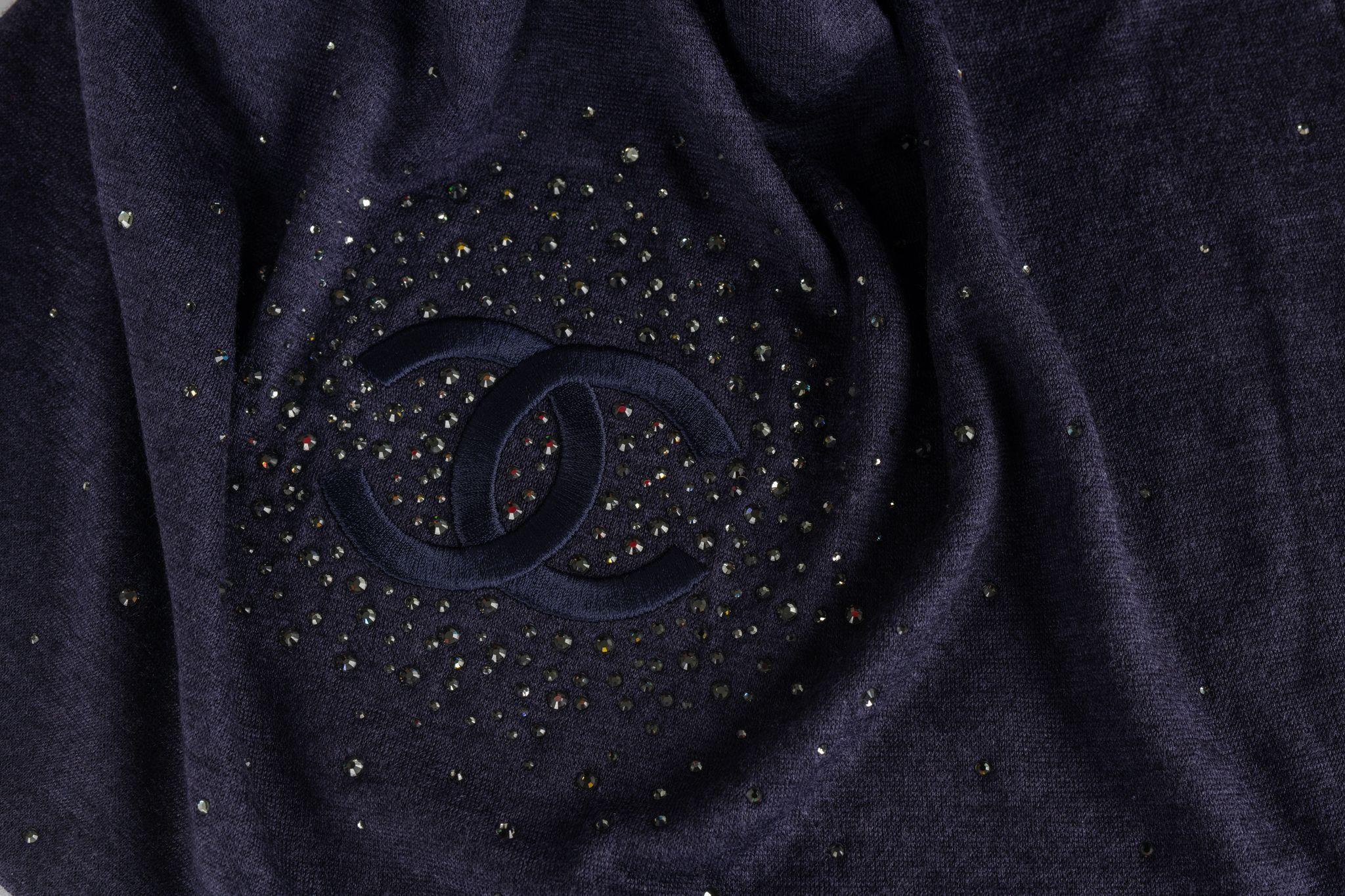 Chanel Cashmere stole in navy with a CC logo in black in the center surrounded by glitter stones. The item is in new condition.