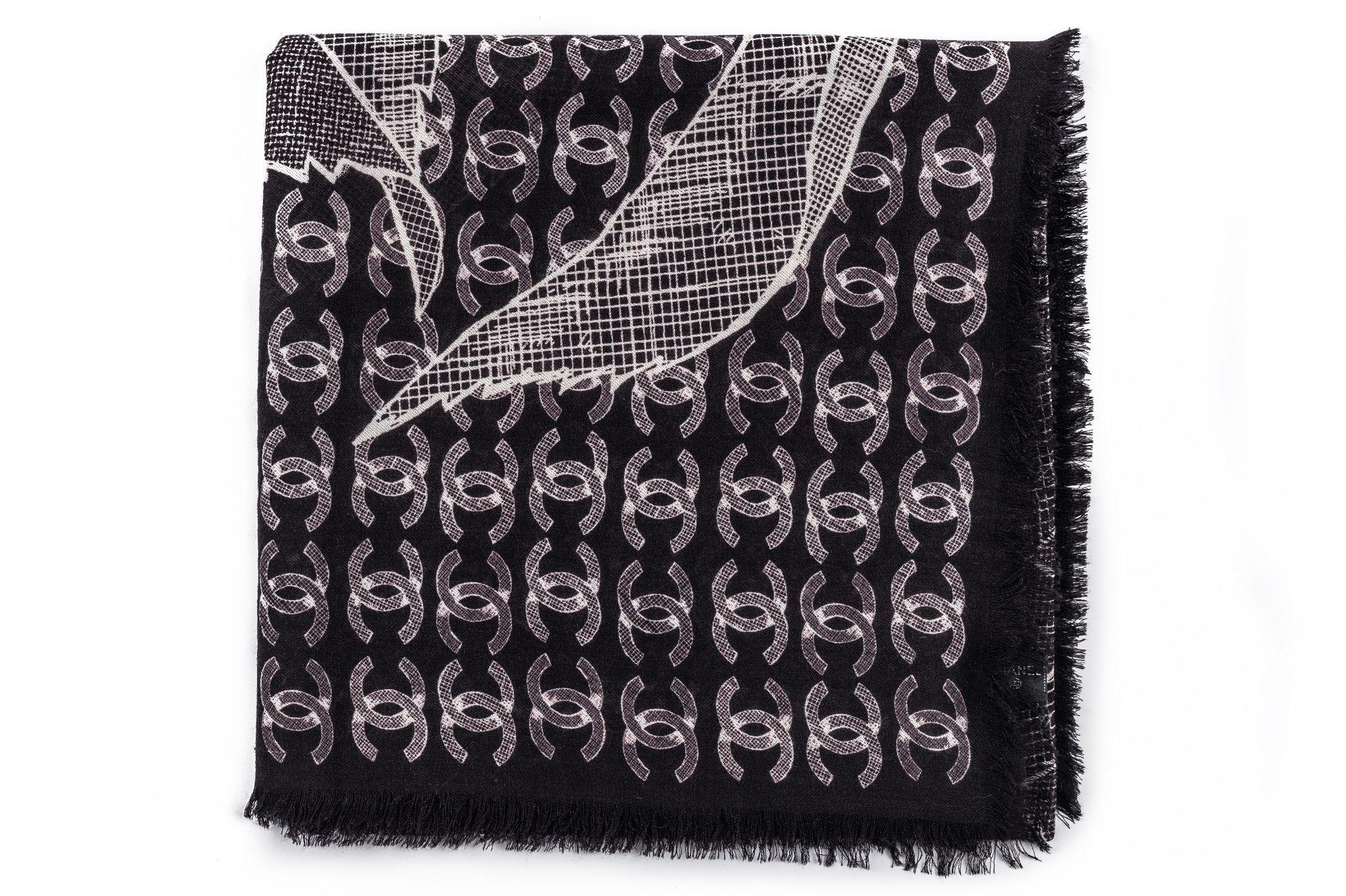 Chanel new Cashmere Shawl in black and white. The pattern features a big Chanel camellia which is surrounded by multiple CC logos. The item is in excellent condition.