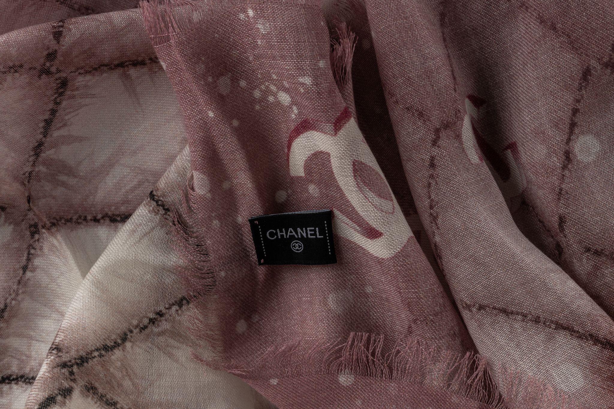 Chanel cashmere shawl in Rosé and Beige. The pattern features a checkered design in beige while it's framed with a rose tone. The item is in newt condition.