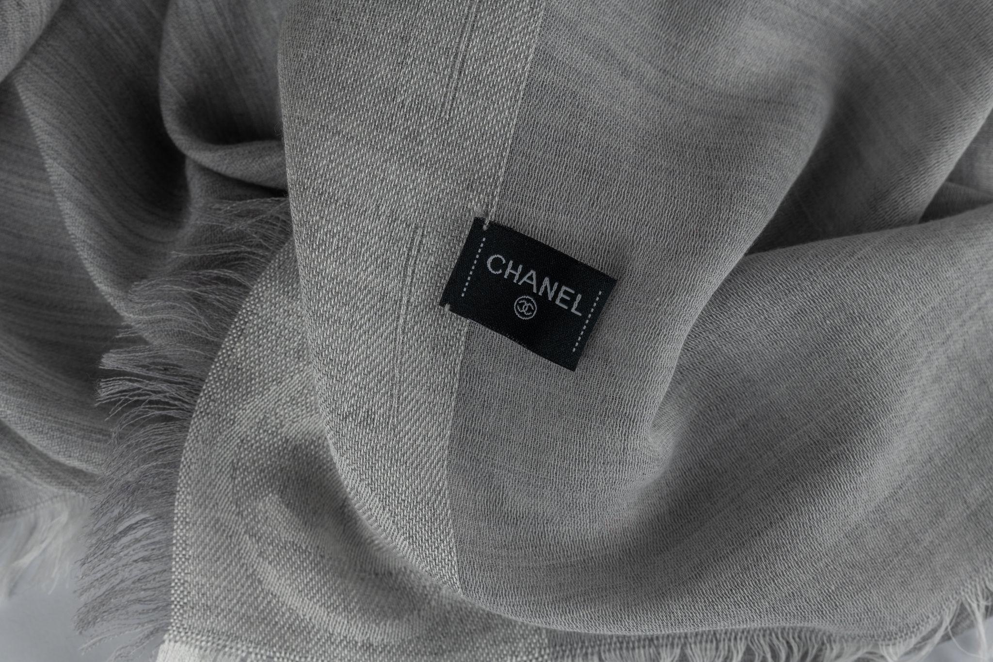 Chanel new grey shawl with white fringe trim. Logo design . Oversize rectangular shape. 100% cashmere .Dry clean only .