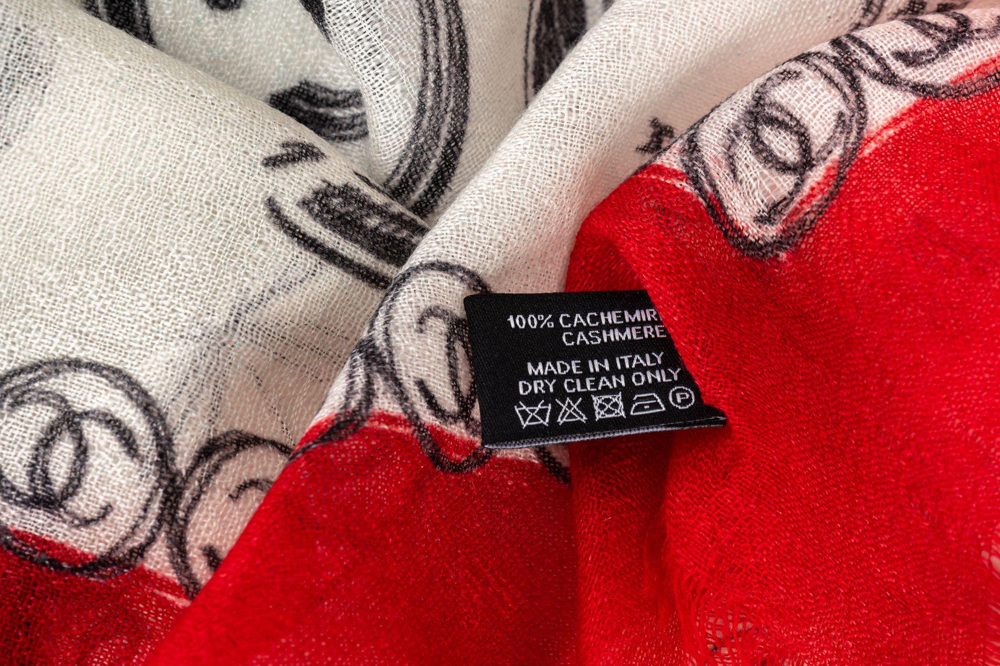 Chanel new cashmere shawl in white with red trim. Black logo drawings. Care tag attached.
