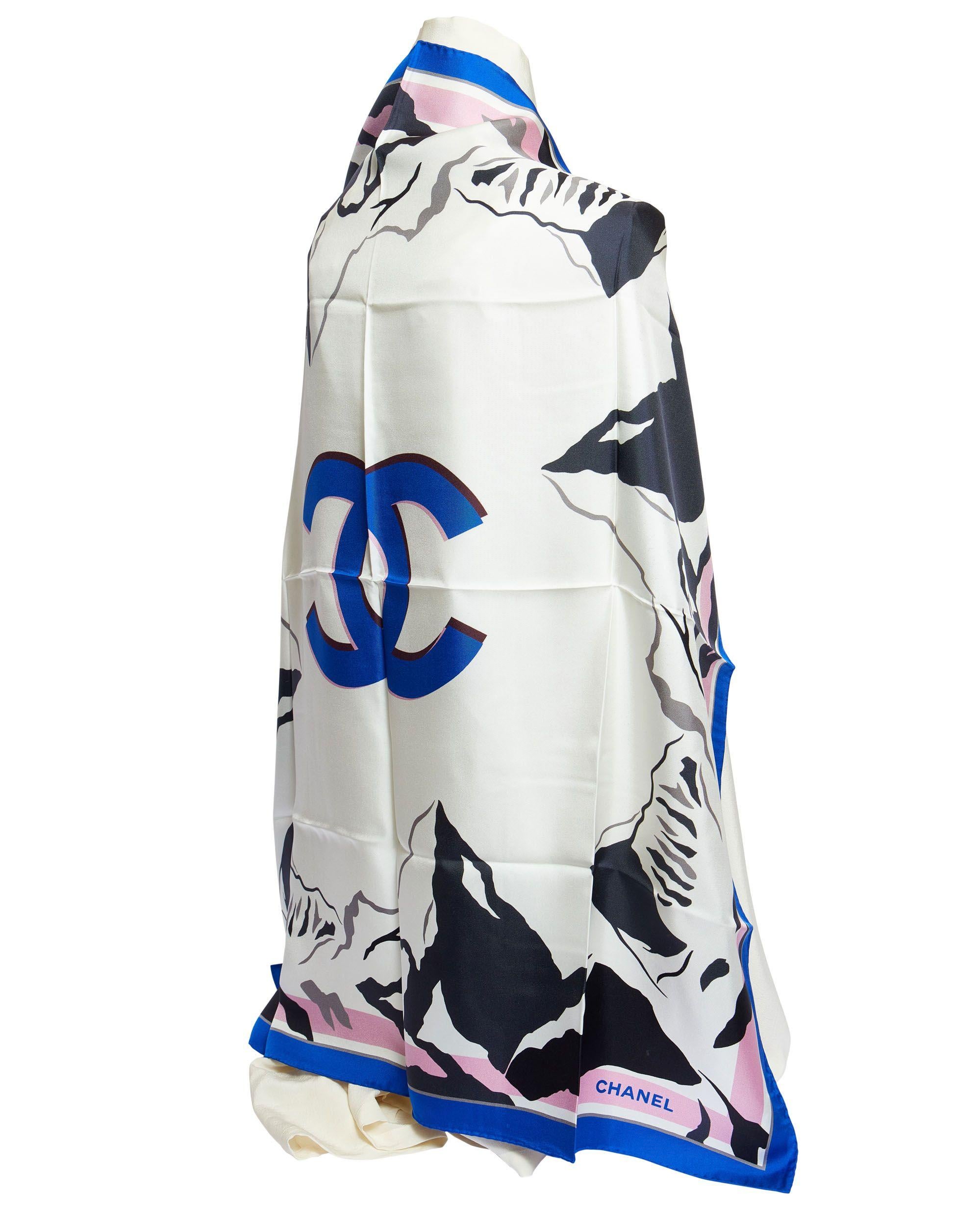 New Chanel silk scarf with big blue CC logo in the center which is surrounded by black mountains like the Alpes. The trim is blue and the edges are hand rolled. The scarf is 100% silk.
