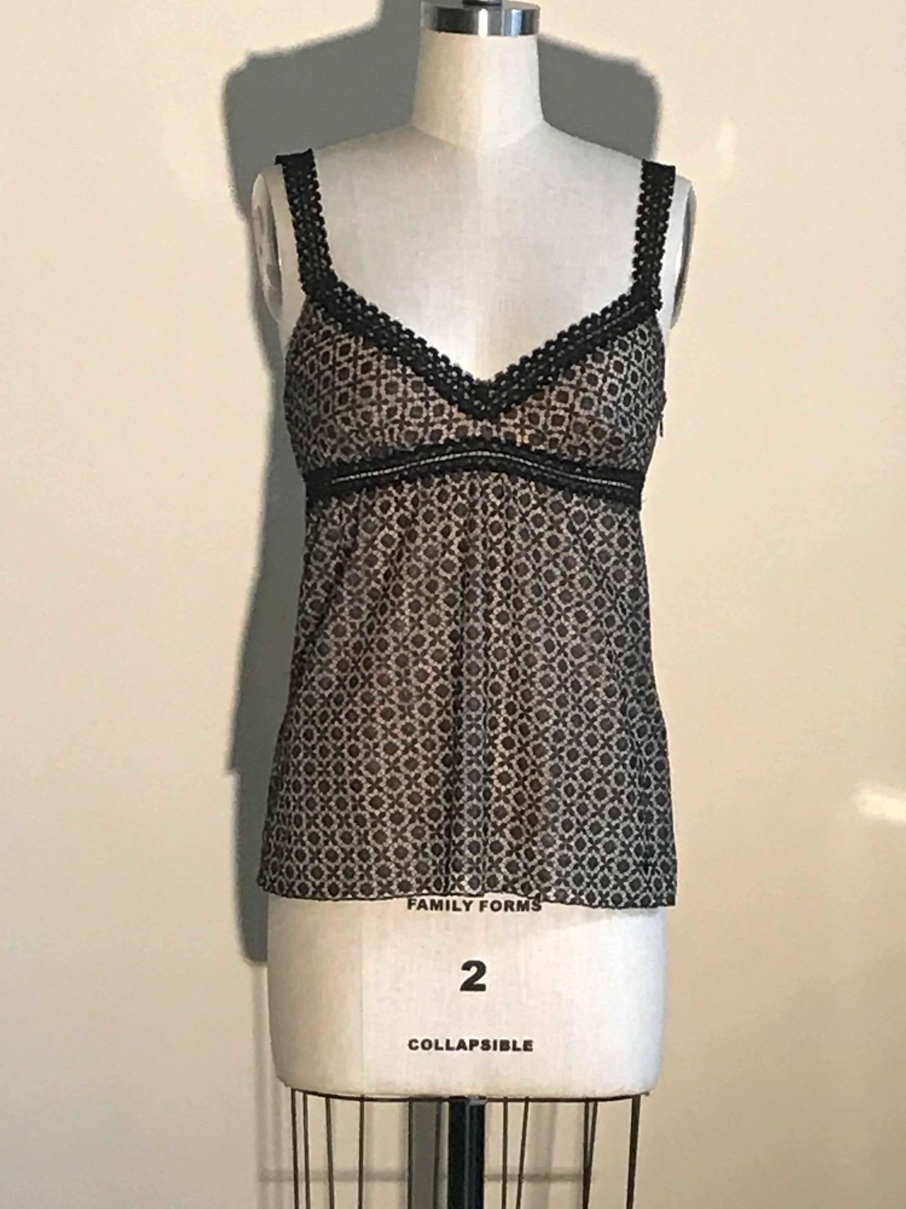 Chanel black geometric lace sleeveless top with nude colored slip style tank lining. Small black CC logo embellishment at side hip. Stretchy under layer, side zip at top layer. 

Outer layer 100% polyester. 
Lining is 84% silk, 16% spandex. 

Made